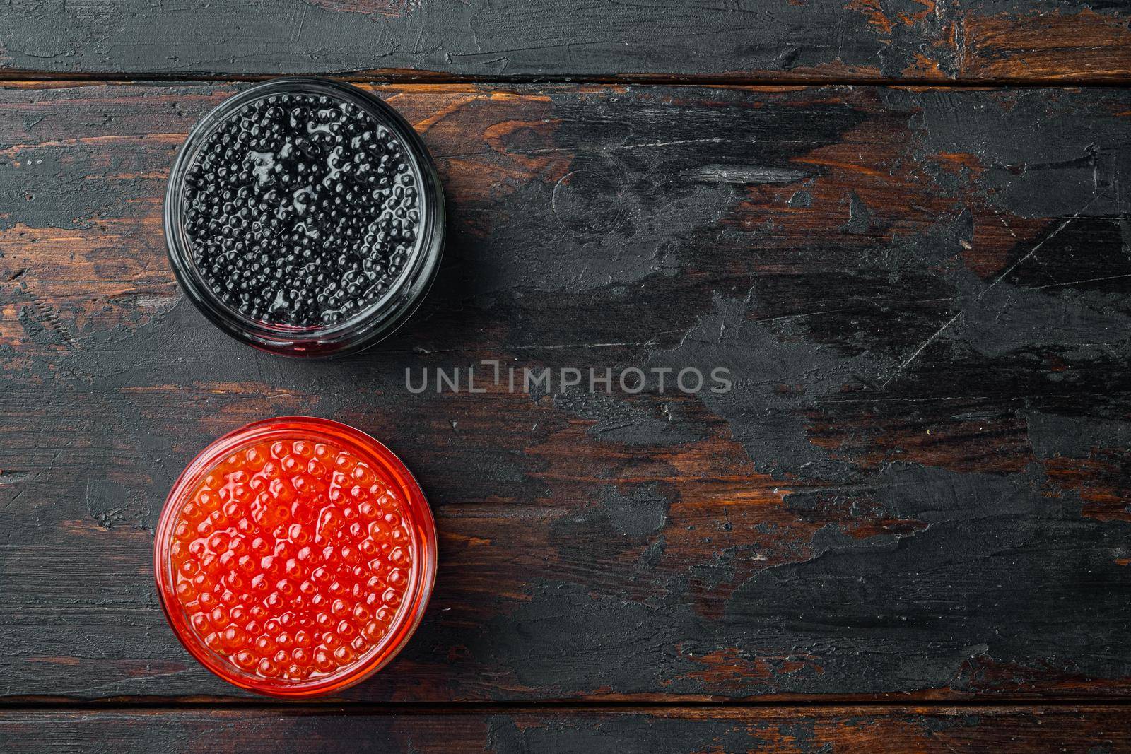 Red and black caviar in glass bowl, on old dark wooden table background, top view flat lay with copy space for text