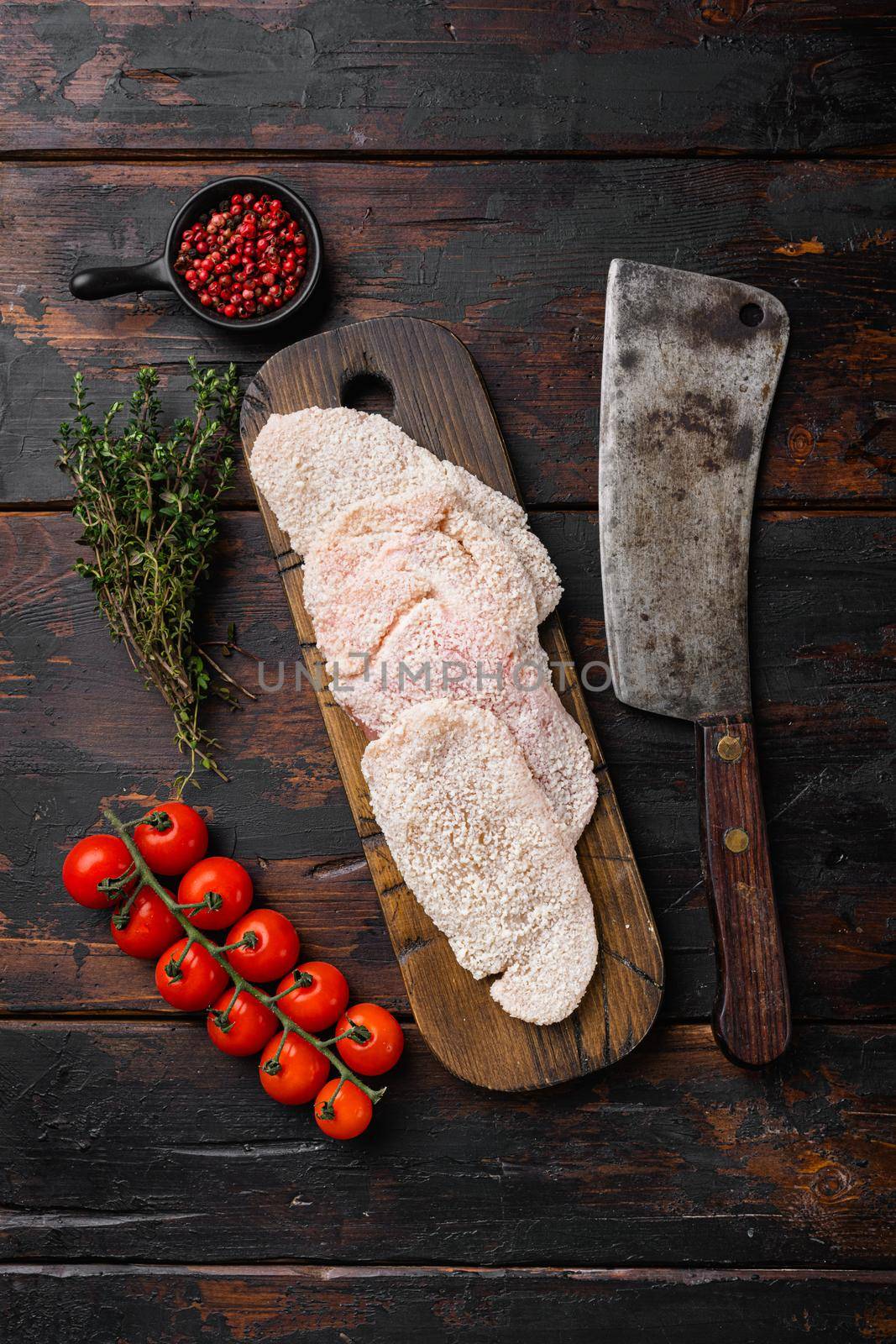 Raw schnitzel chicken meat, on old dark wooden table background, top view flat lay, with copy space for text