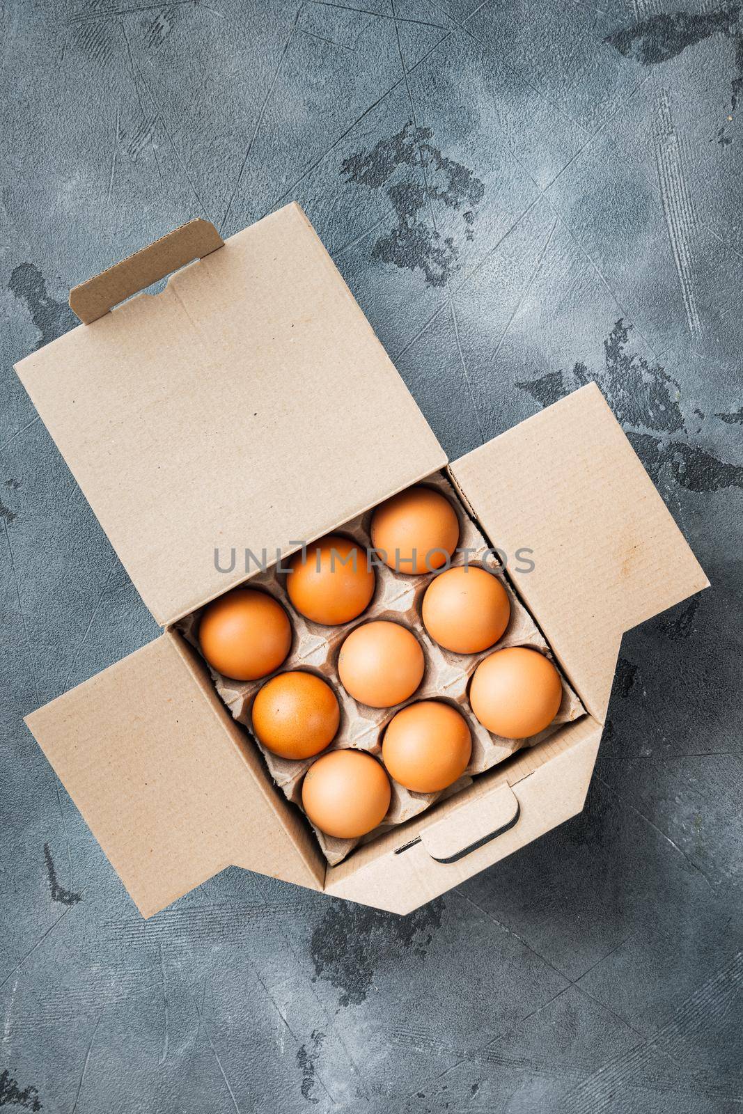Fresh eggs on paper egg box set, on gray background, top view flat lay