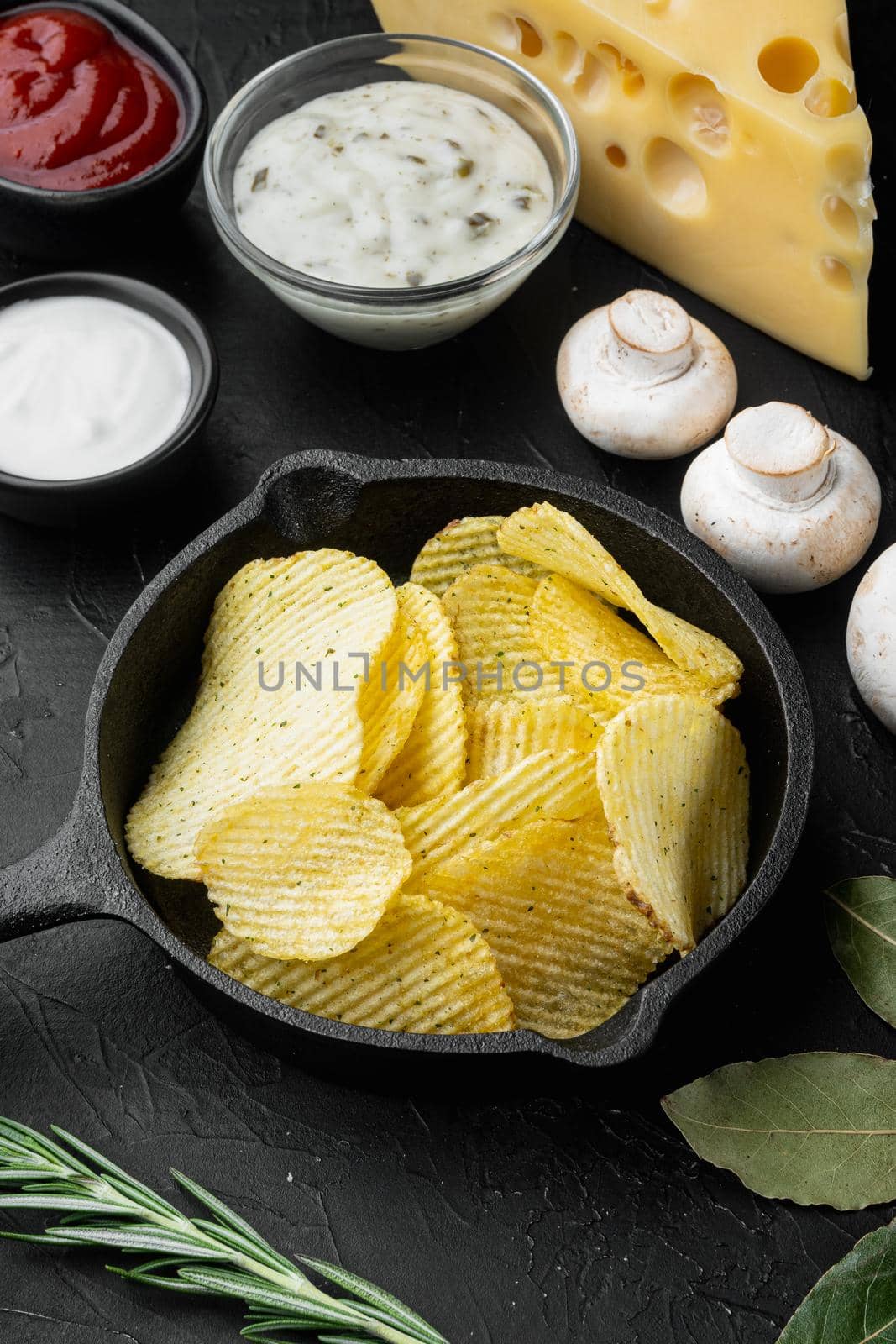 Potatoe chips with Cheese and Onion, with sour cream, on black stone background by Ilianesolenyi