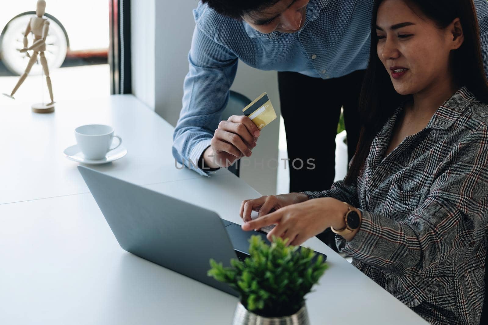 Asian couple at home shopping online with laptop and credit card.