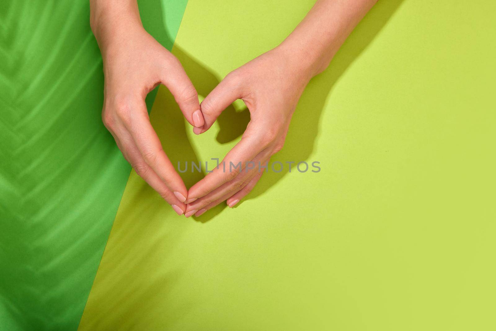 Hands making heart symbol on green background by Demkat