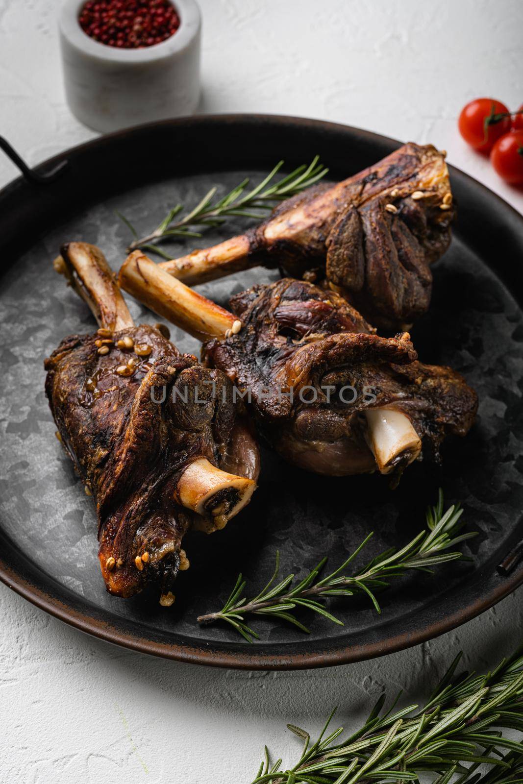 Braised Lamb Shanks with Sauce and Herbs set, on white stone table background