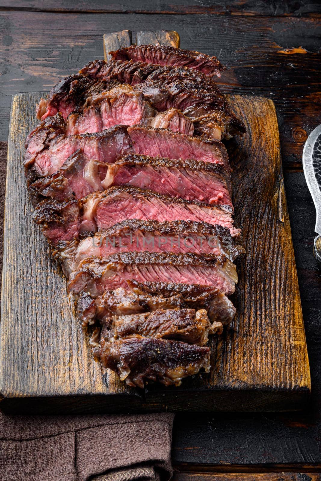 Fresh grilled meat. Grilled beef steak medium rare black angus rib eye steak, on wooden serving board, on old dark wooden table background by Ilianesolenyi