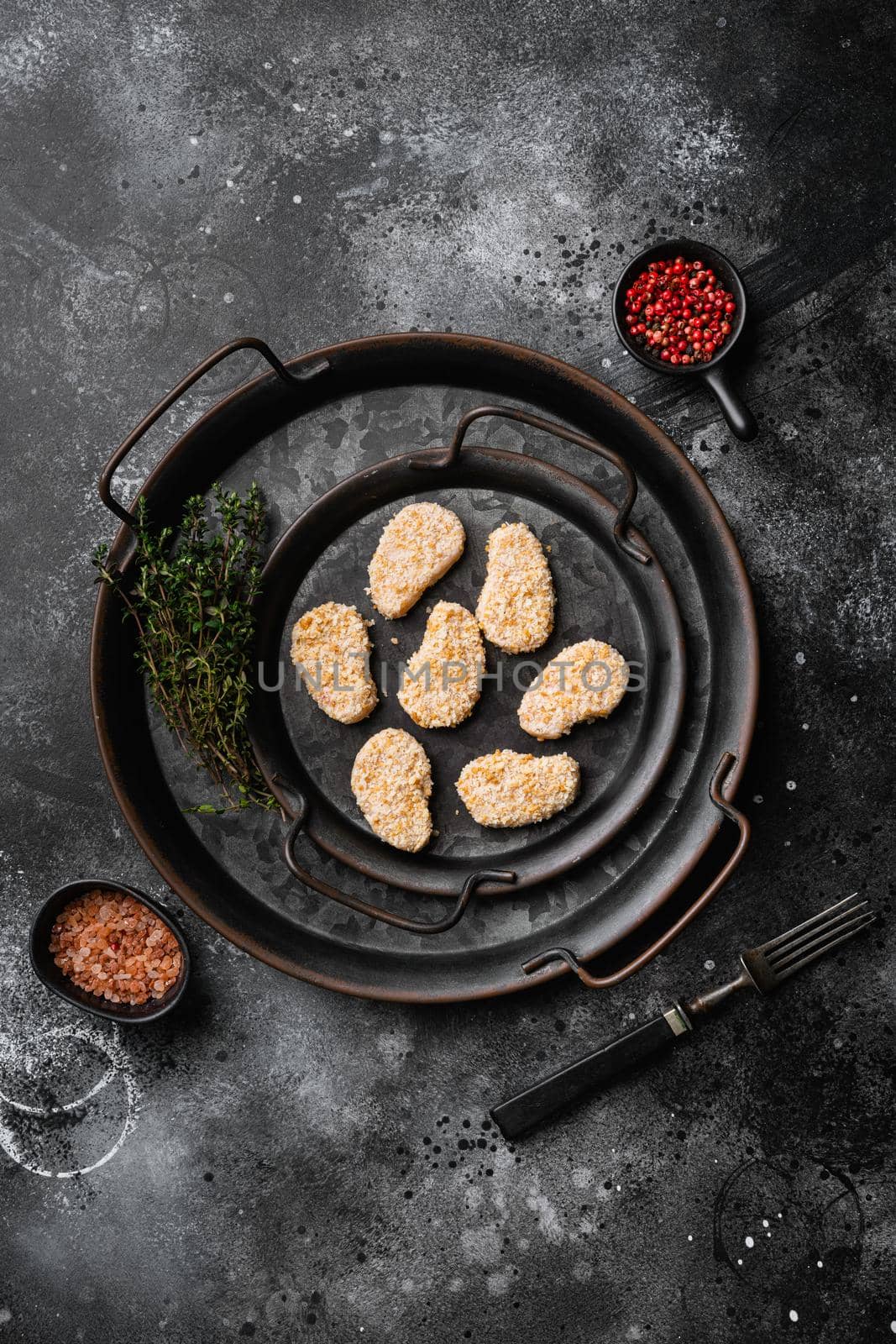 Raw chicken nuggets meat, on black dark stone table background, top view flat lay