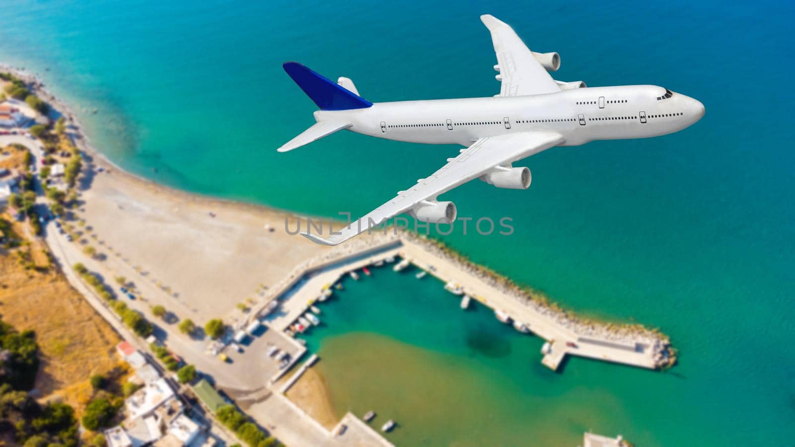 Aerial top down view of an airplane flying over blue sea as a travel concept with copy space by Andelov13