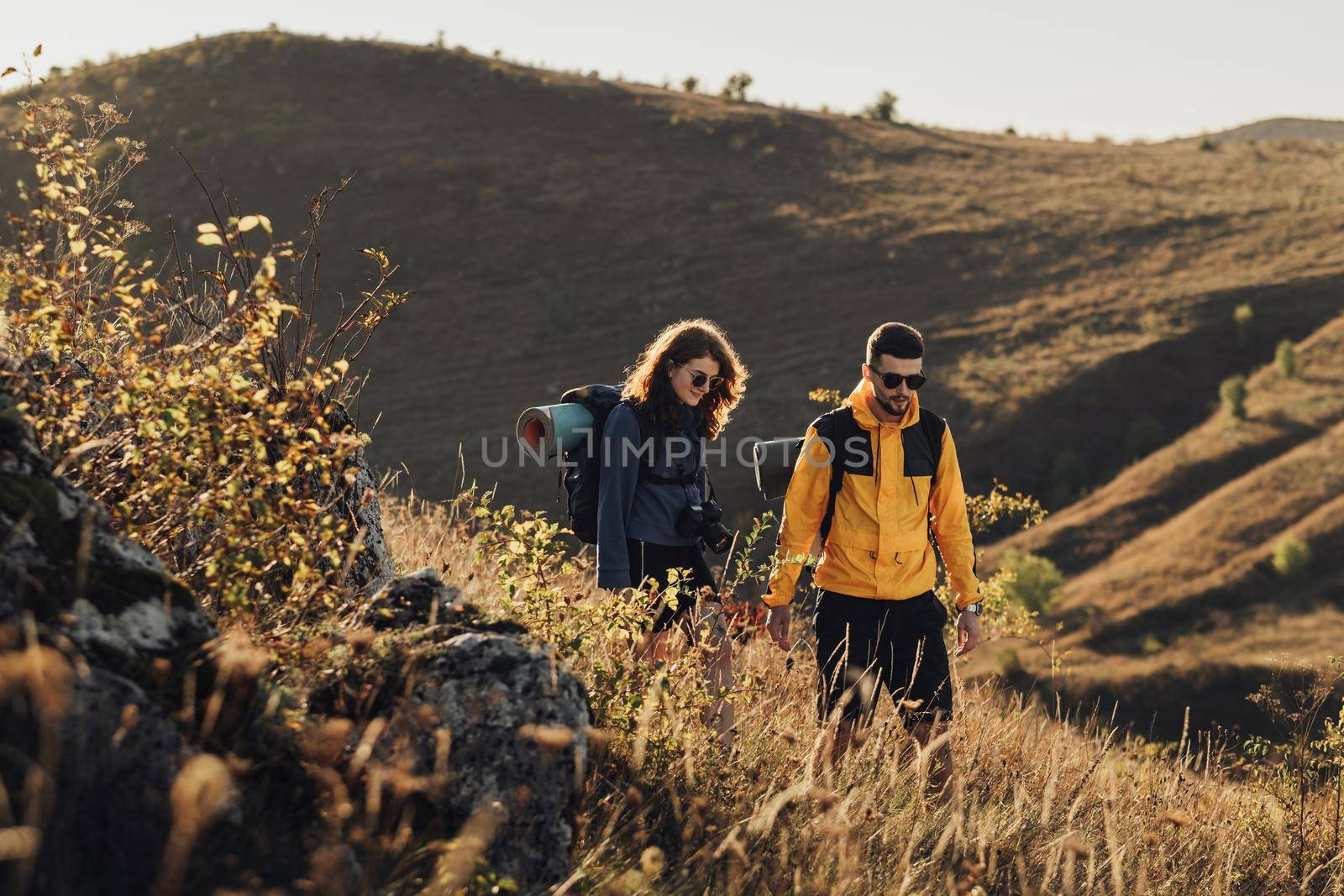 Man and Woman Holding by Hands While Hiking Together on Hill During Sunset, Young Couple Enjoy Their Trip