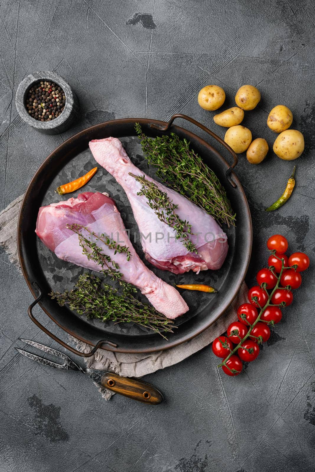 Fresh turkey legs with ingredients for cooking, on gray stone table background, top view flat lay, with copy space for text by Ilianesolenyi