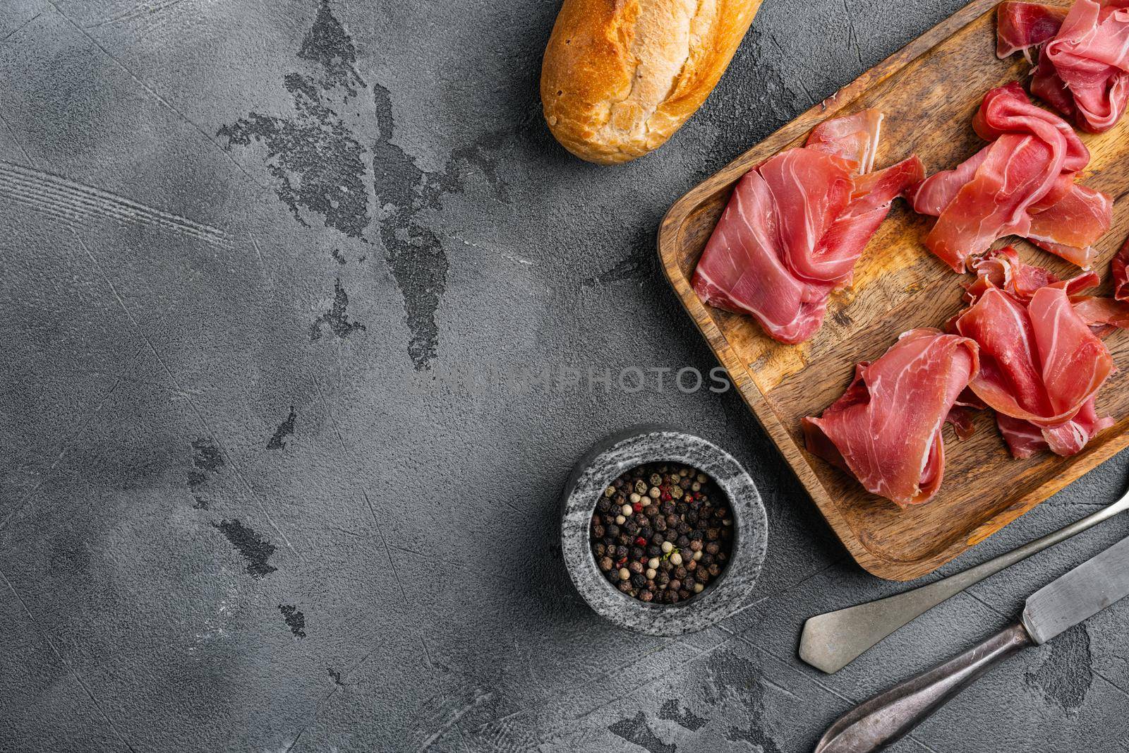 Delicious Spanish jamon or ham, on gray stone table background, top view flat lay, with copy space for text