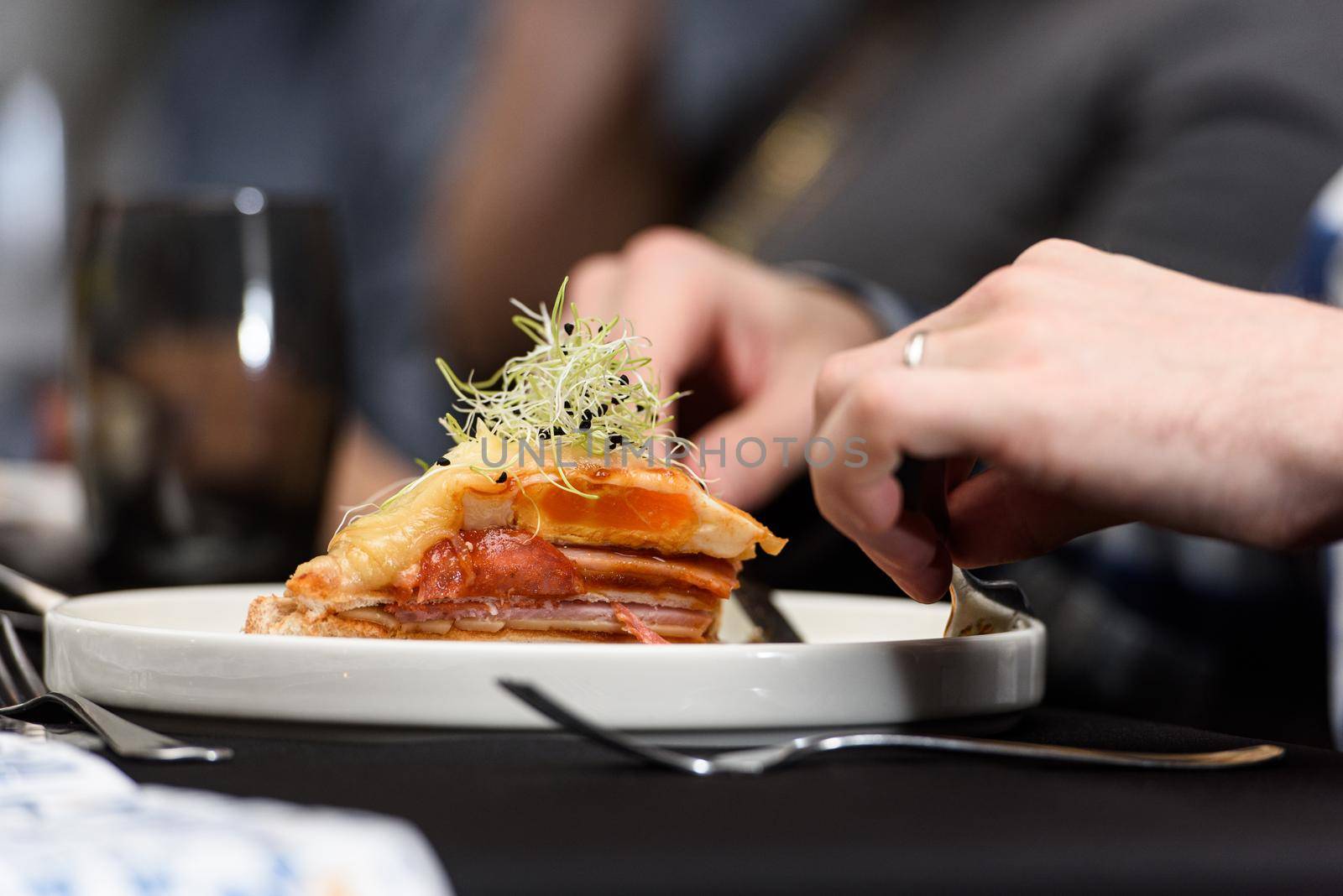 Man eating Francesinha, traditional Portuguese sandwich in a restaurant. National cuisine concept.