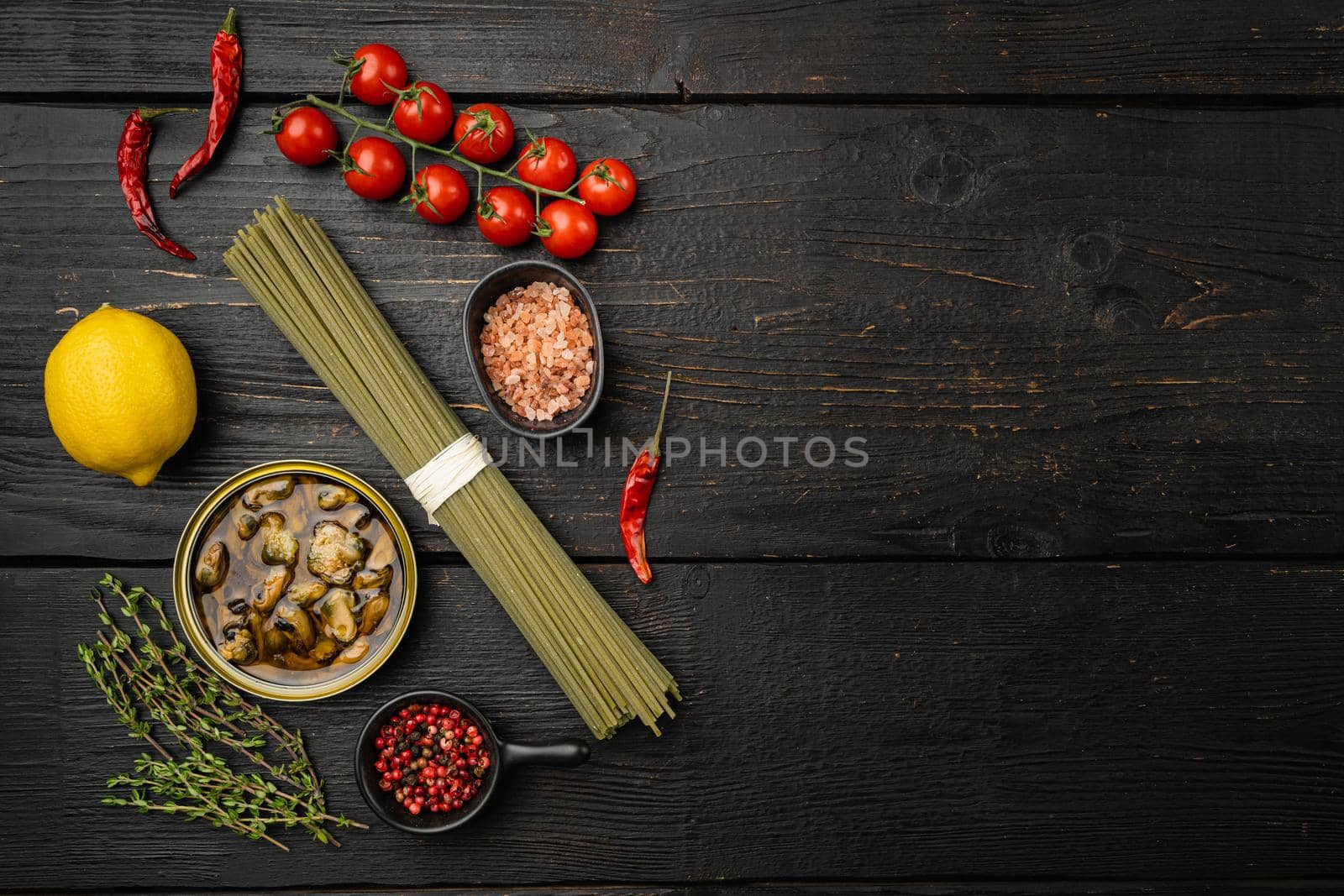 Ingredients for preparation spaghetti with calms or mussels, on black wooden table background, top view flat lay, with copy space for text by Ilianesolenyi