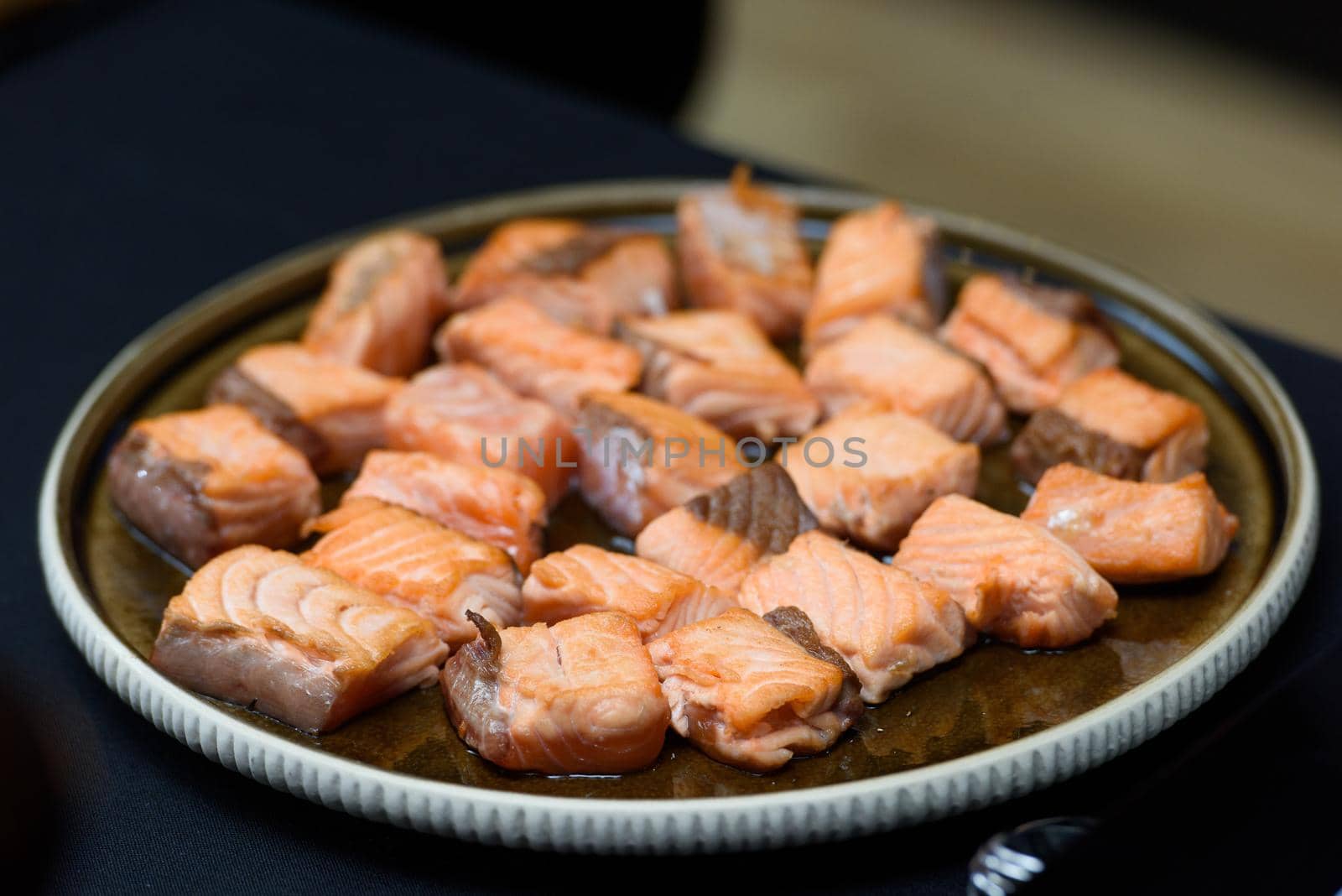 Fried salmon small pieces. slices, cubes. closeup on a ceramic plate.