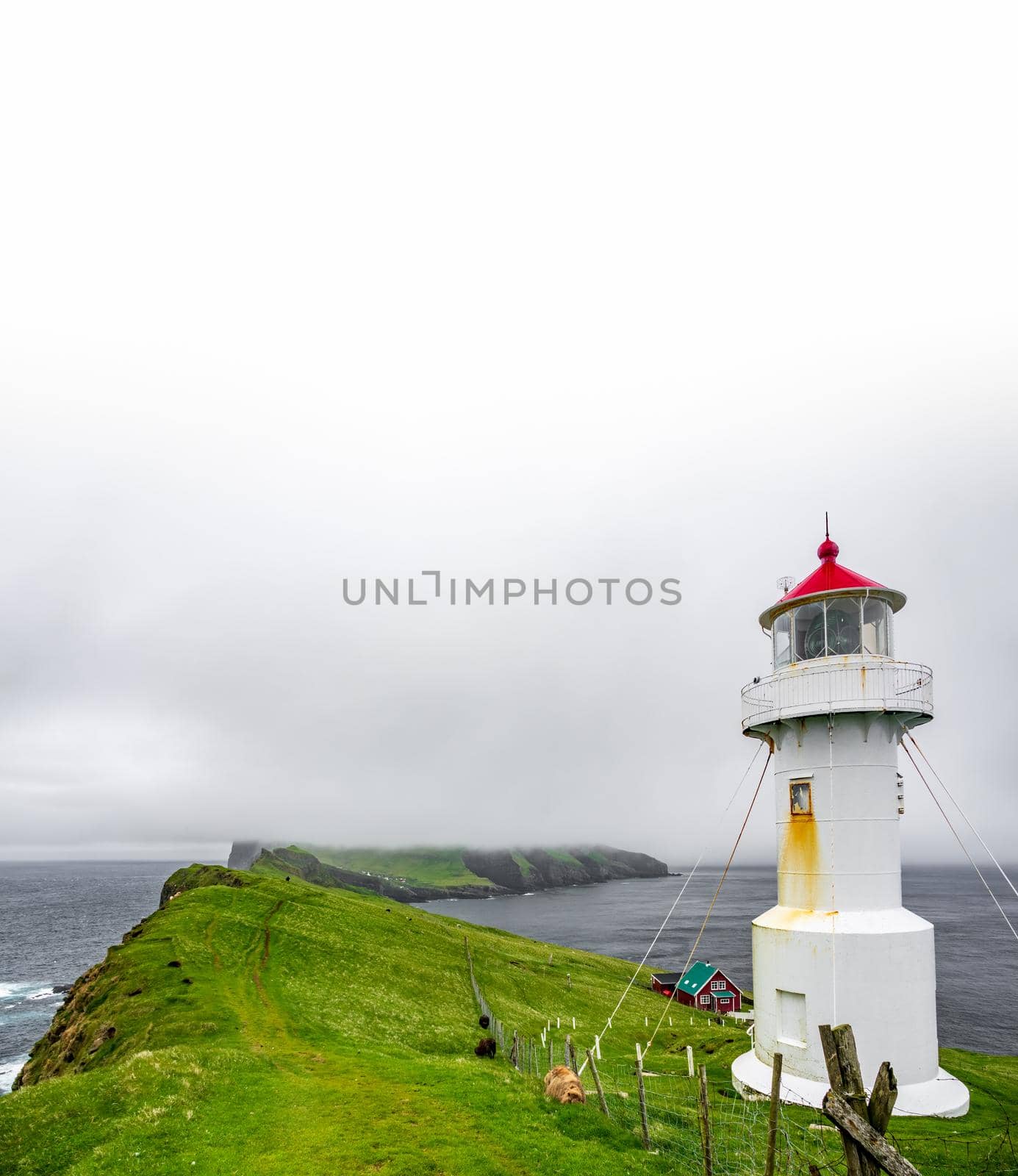 Lighthouse at the end of the island under white sky for text space