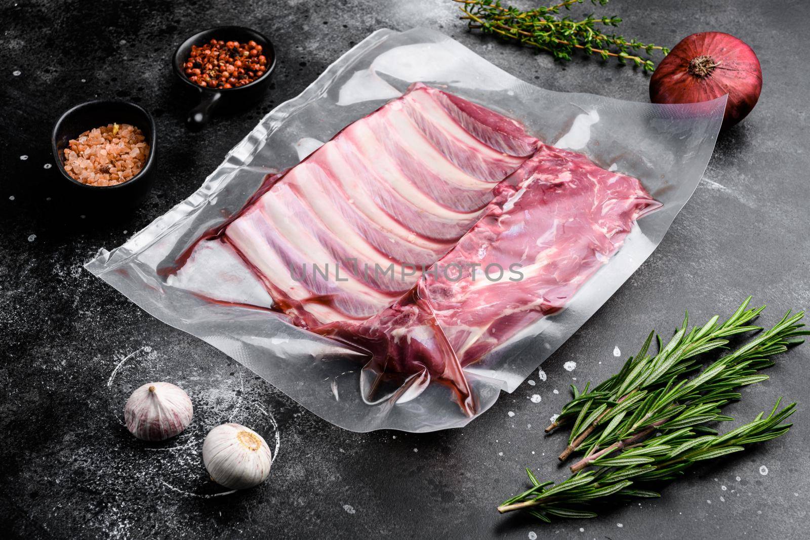 Supermarket packaged raw lamb rib rack set, on black dark stone table background