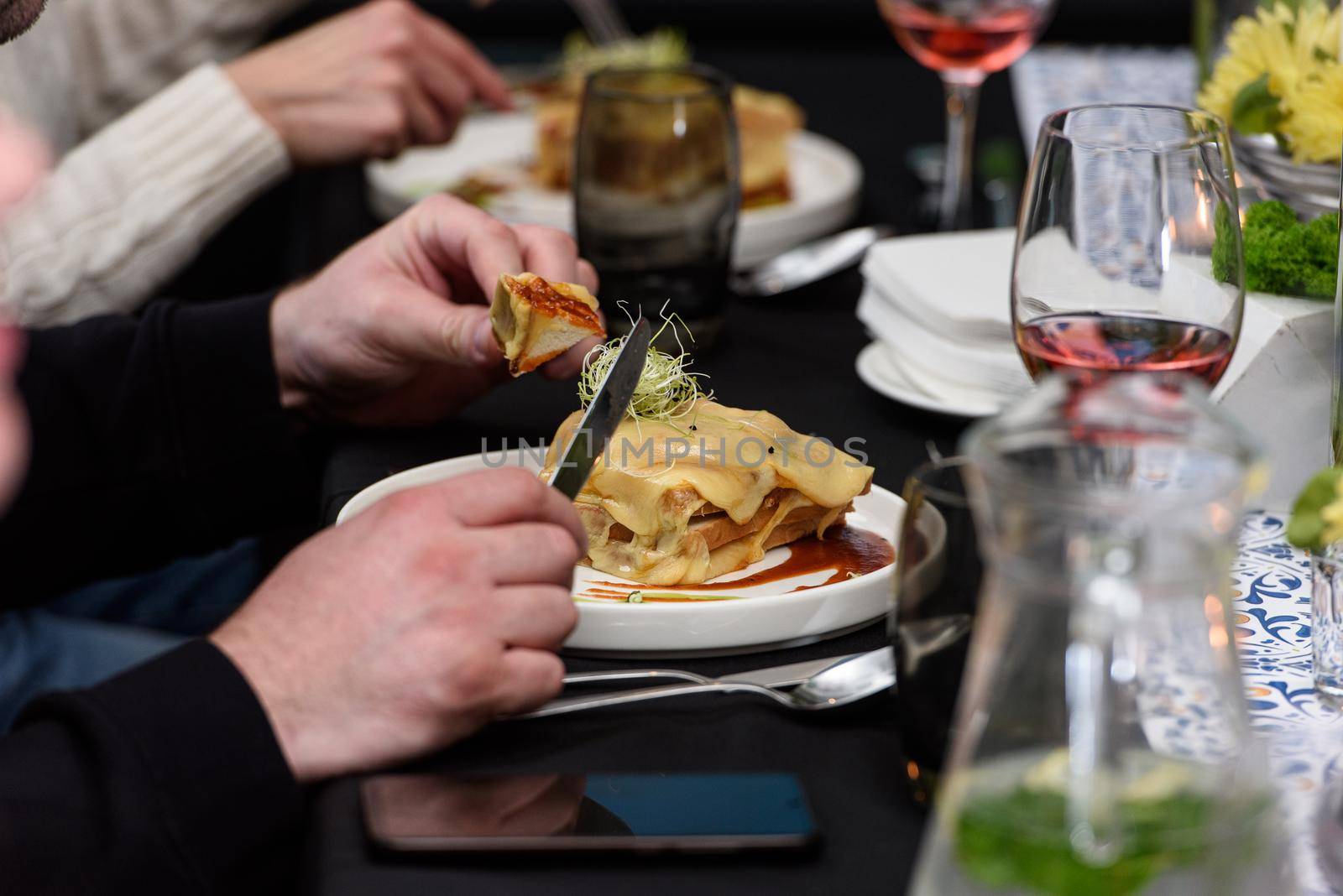 Man eating Francesinha, traditional Portuguese sandwich in a restaurant. National cuisine concept.