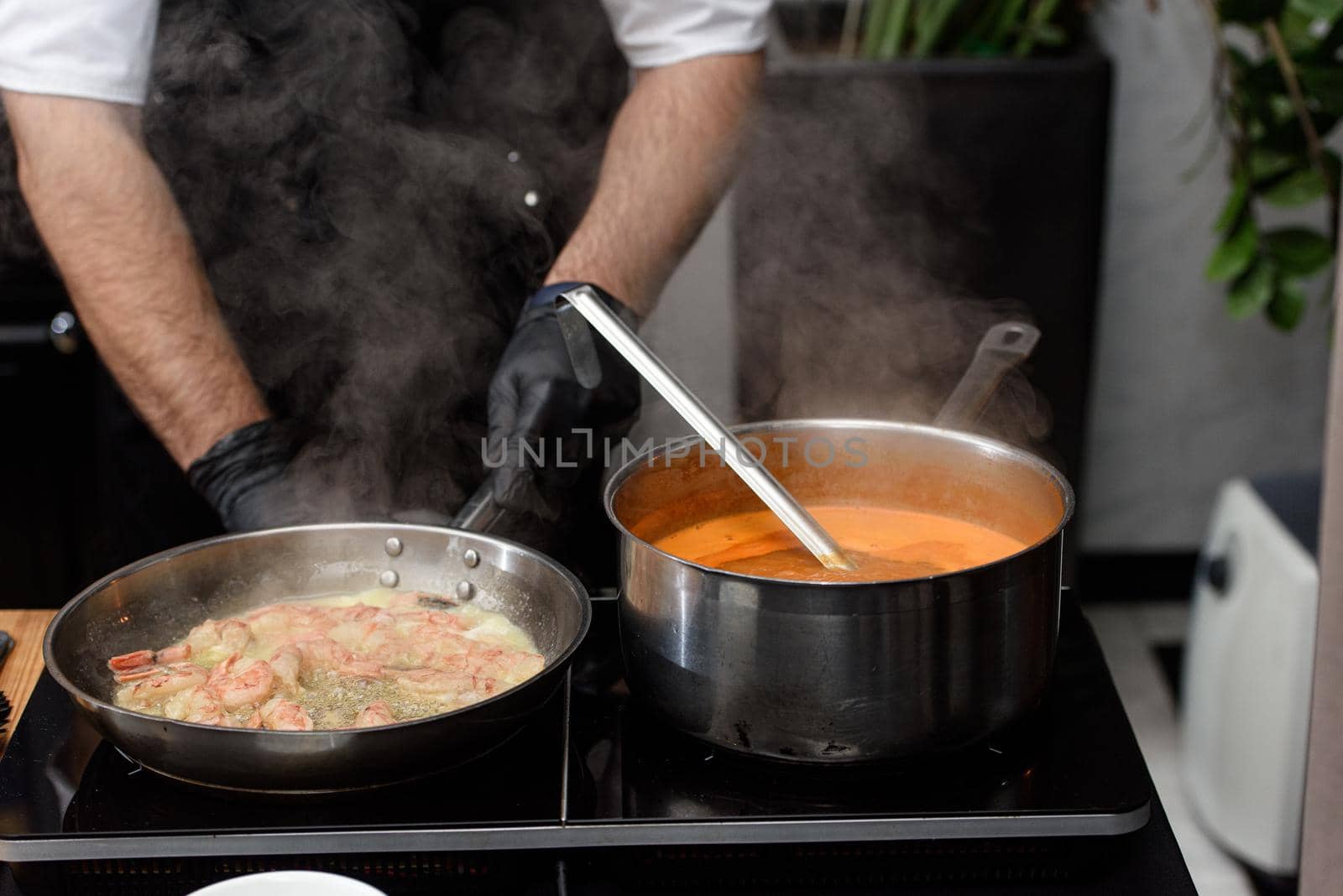 cooking process of Suquet de Peix soup with potatoes, herbs and fish with the addition of picada close-up in a saucepan on the table. horizontal