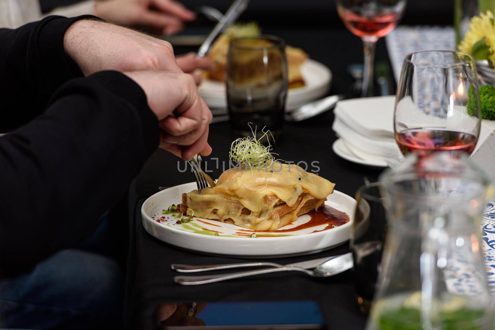 Man eating Francesinha, traditional Portuguese sandwich in a restaurant. National cuisine concept.