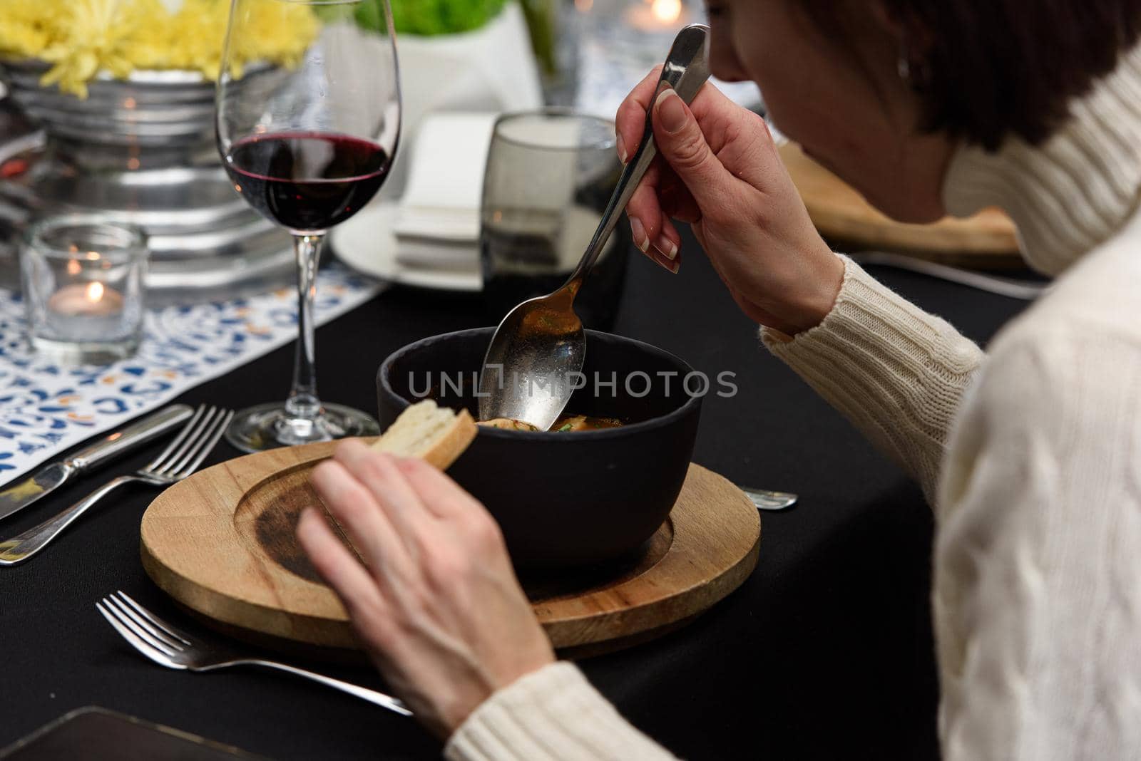 Woman eating seafood spicy soup with potatoes, shrimps, herbs and fish from a picad closeup in a pan served with toast. horizontal. Served in a restaurant by Ashtray25