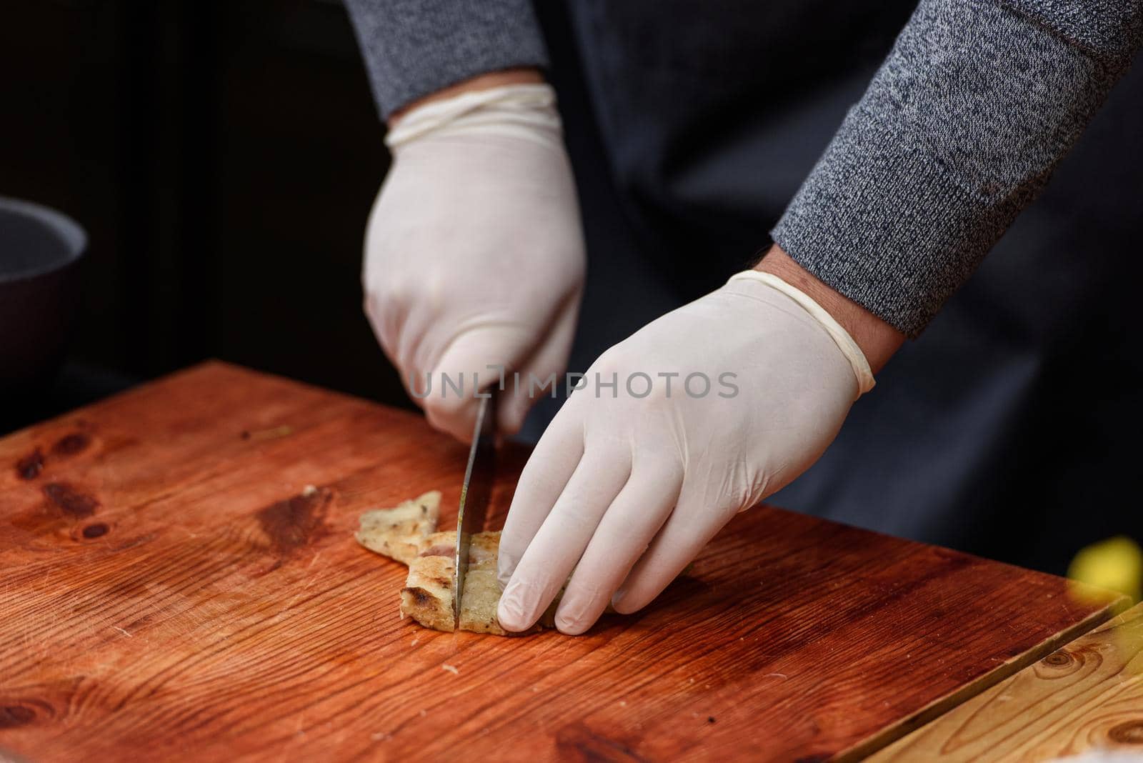 man cuts fried fish, cooking process of Suquet de Peix soup with potatoes.