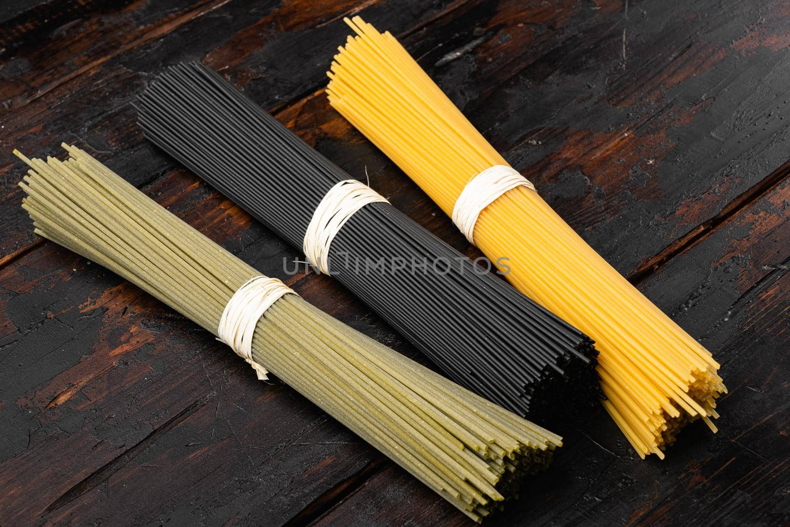 Colored spaghetti raw dry set, on old dark wooden table background