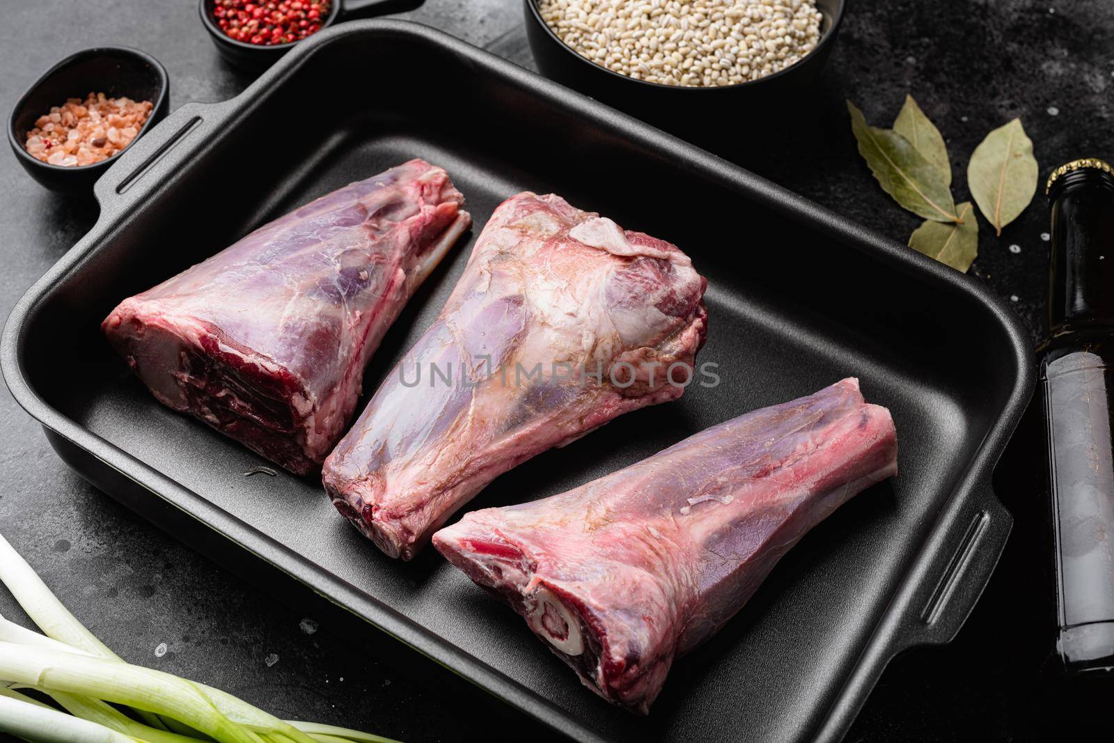 Raw lamb shanks meat, on black dark stone table background by Ilianesolenyi