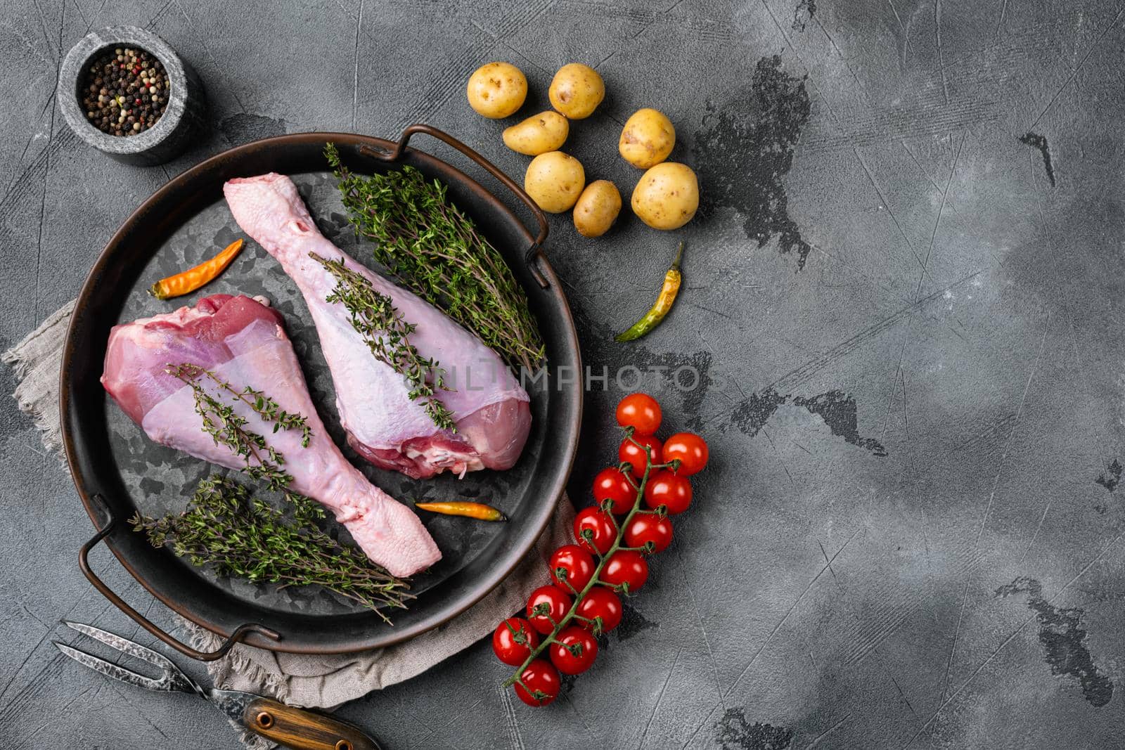 Fresh turkey legs with ingredients for cooking set, on gray stone table background, top view flat lay, with copy space for text