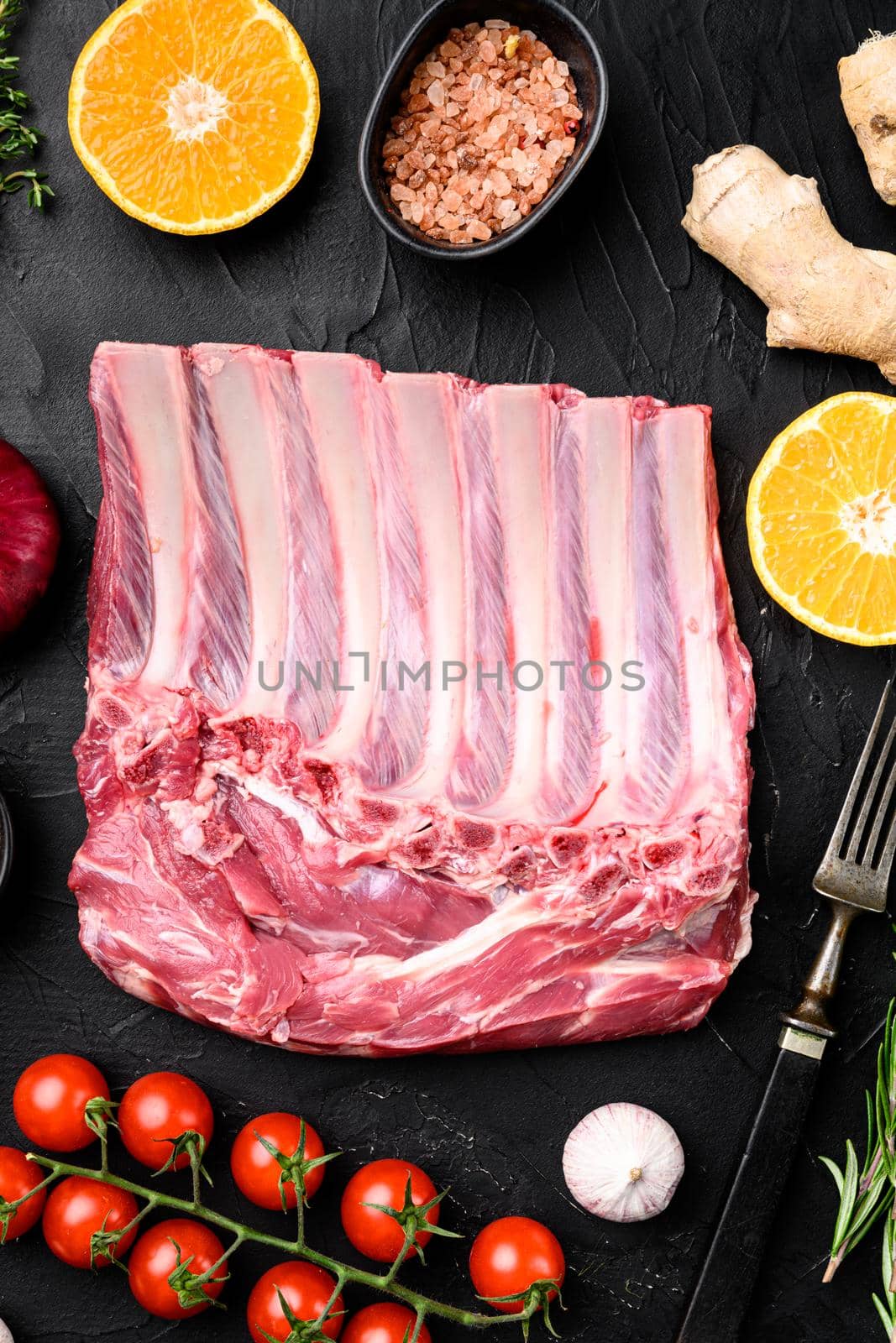 Frenched rack of lamb Mutton set, on black dark stone table background, top view flat lay