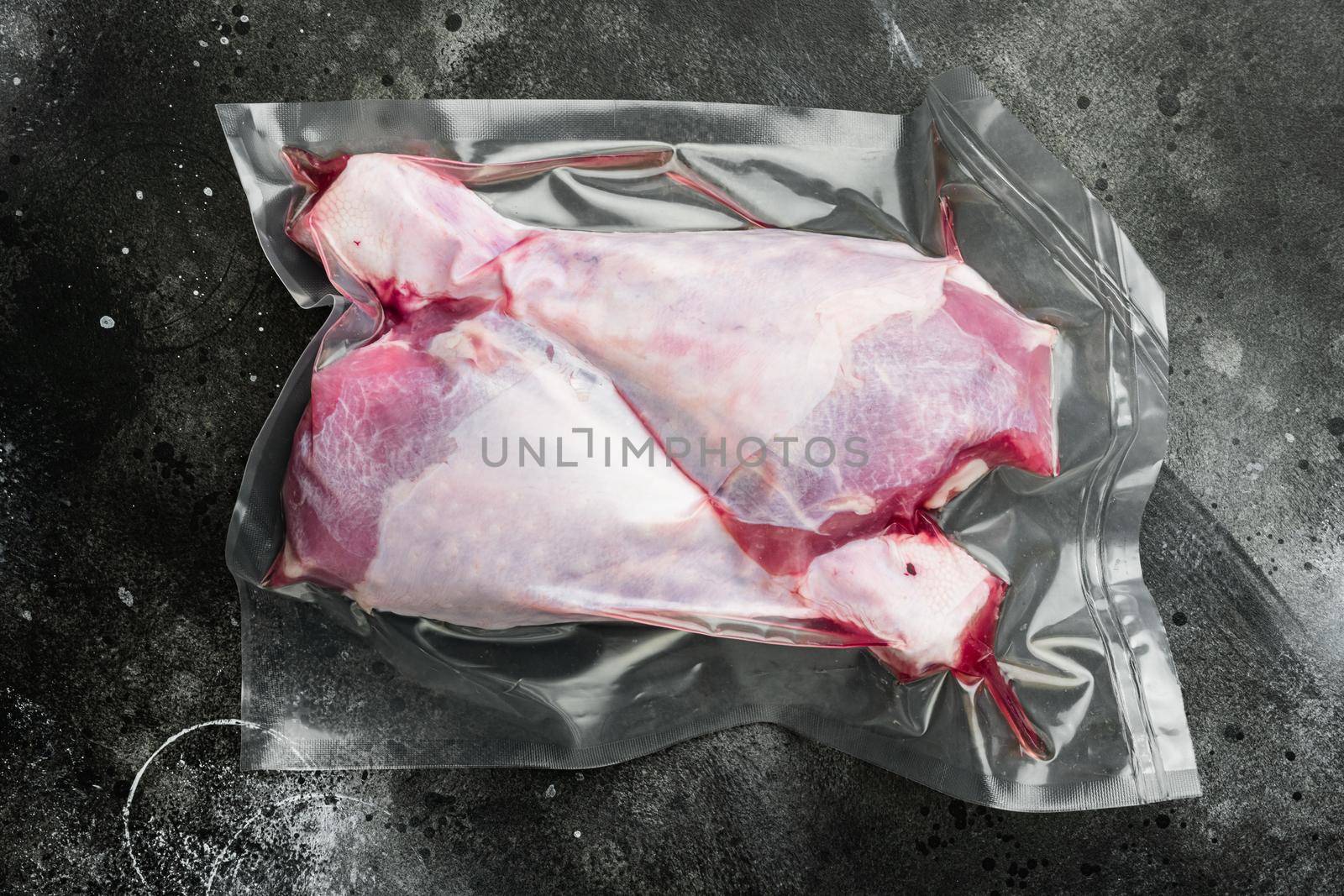 Turkey drumstick meat vacuum pack, on black dark stone table background by Ilianesolenyi