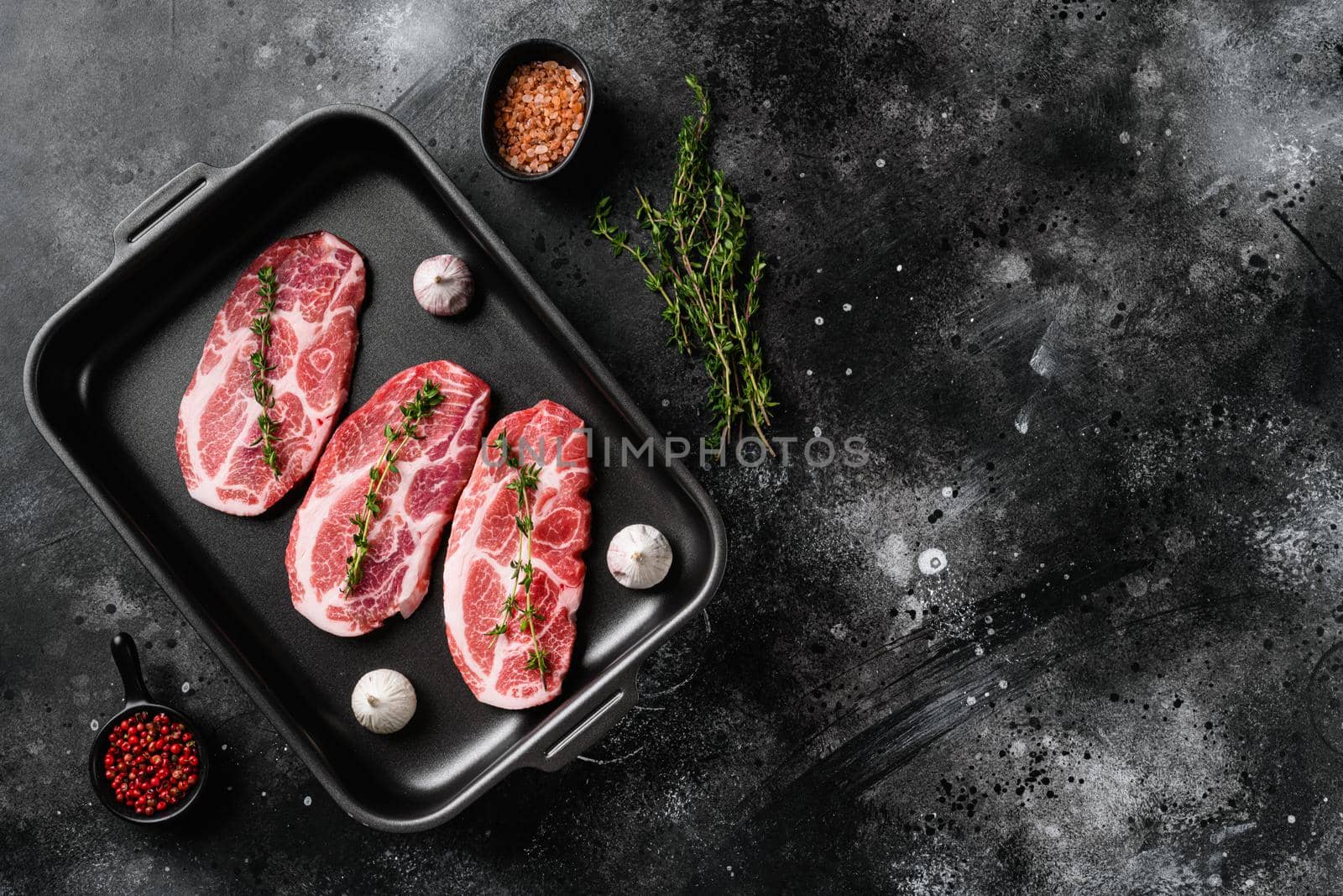 Slices pork loin with herbs set, on black dark stone table background, top view flat lay, with copy space for text