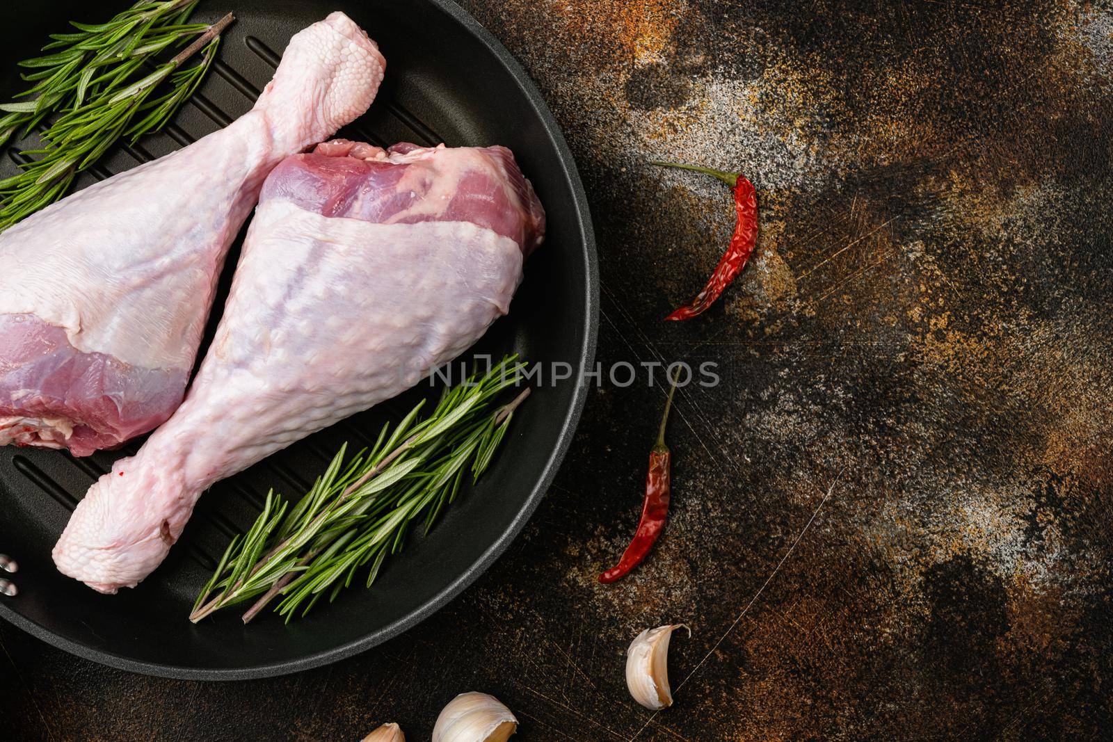 Fresh uncooked turkey legs, on frying cast iron pan, on old dark rustic table background, top view flat lay, with copy space for text by Ilianesolenyi