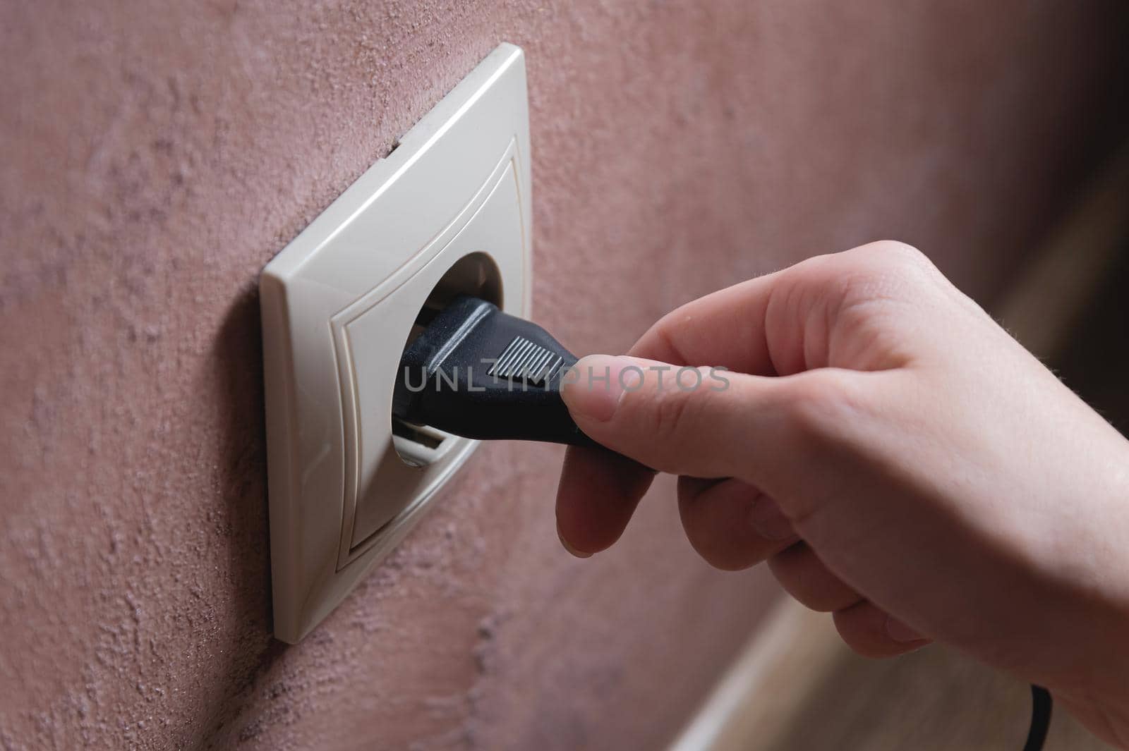 A female hand inserts an electric plug into a euro-format socket close-up by yanik88