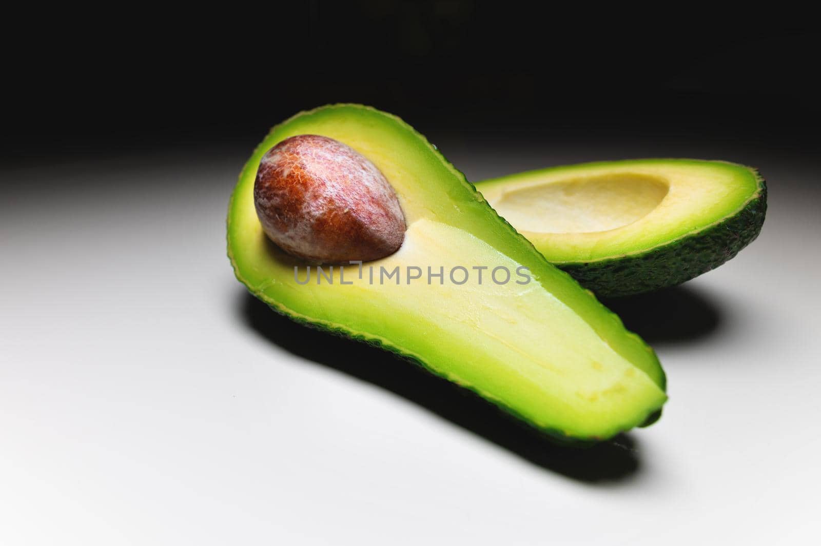 Avocado on old wooden table.Halfs on wooden bowl. Fruits healthy food concept