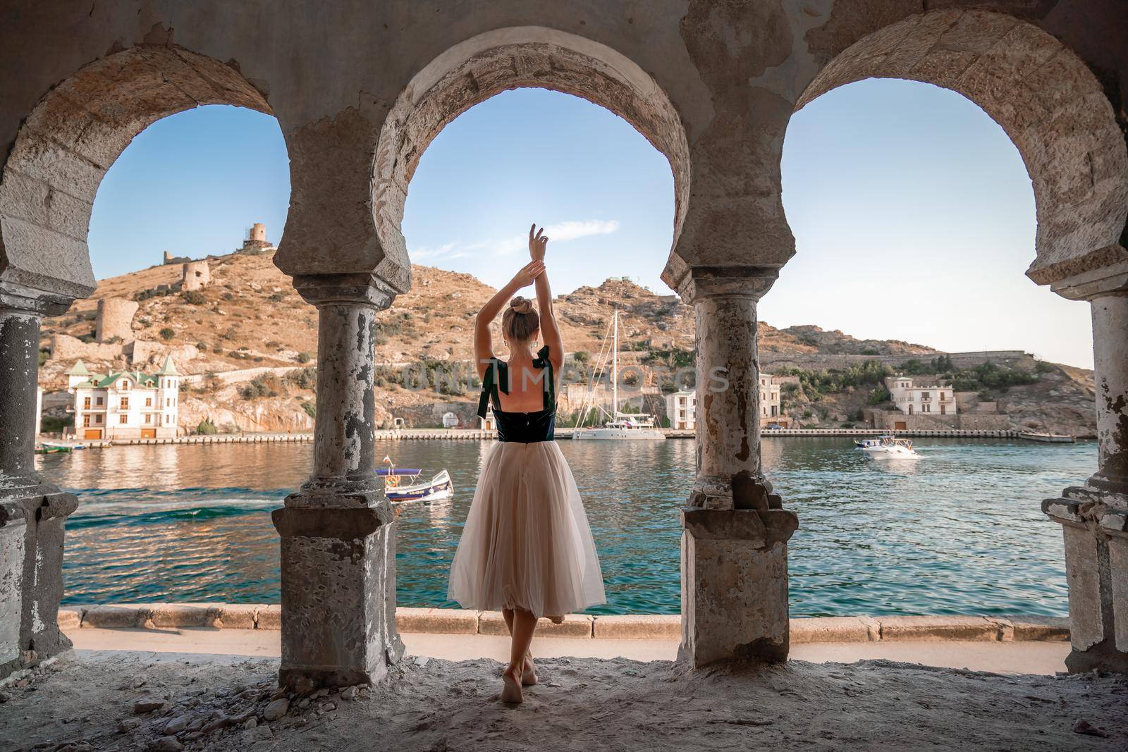 Side view portrait of a relaxed woman breathing fresh air at the seaside. She stands near the old column. by Matiunina