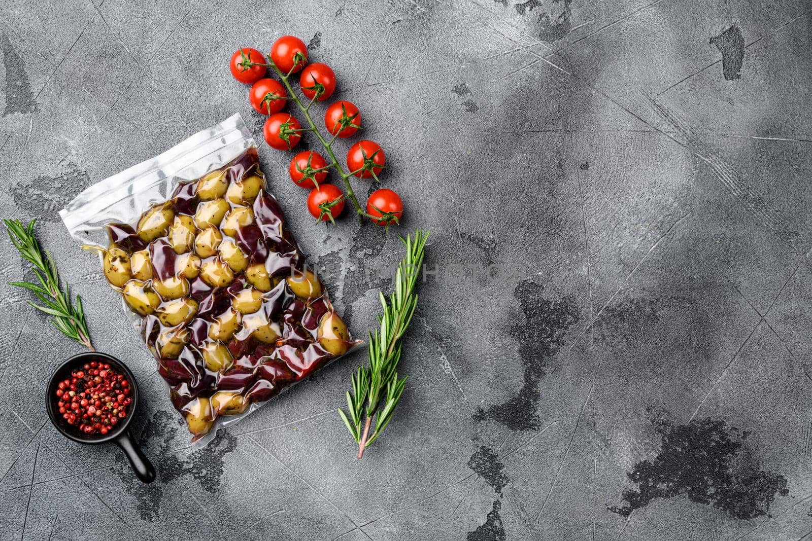 Olives in vacuum pack no label, on gray stone table background, top view flat lay, with copy space for text by Ilianesolenyi