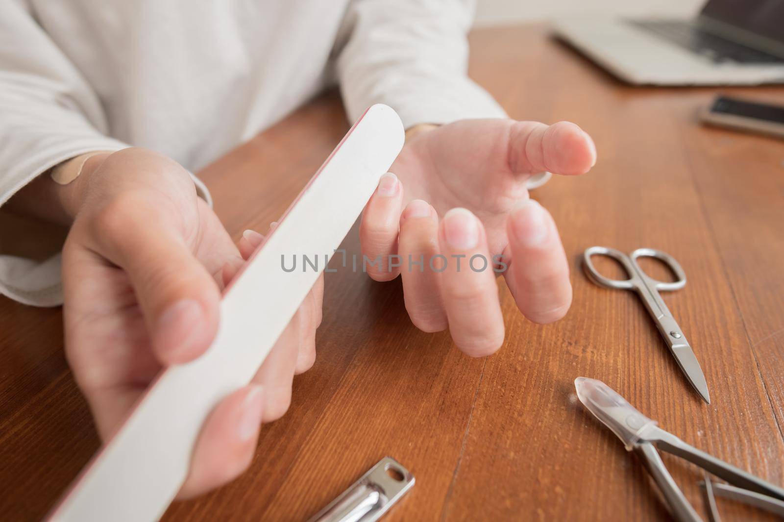 Close-up of hand of caucasian young woman doing manicure at home with nail supplies