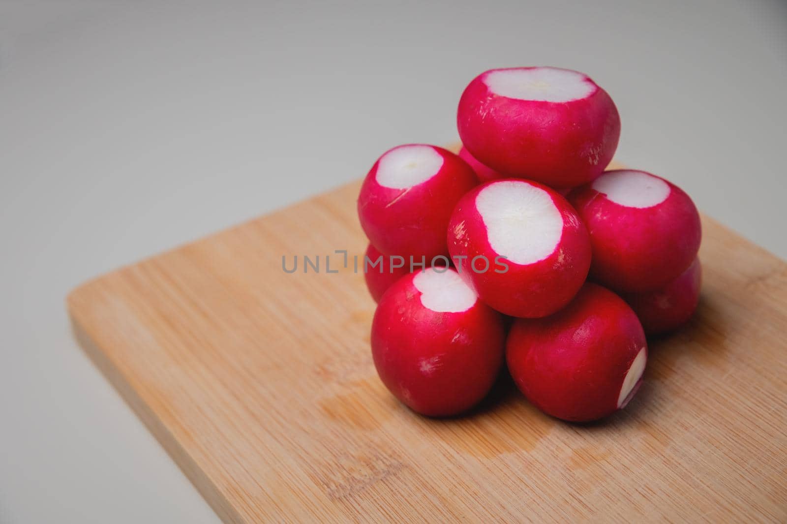 several bright fresh bunch of radishes lies on a wooden board on the table by yanik88