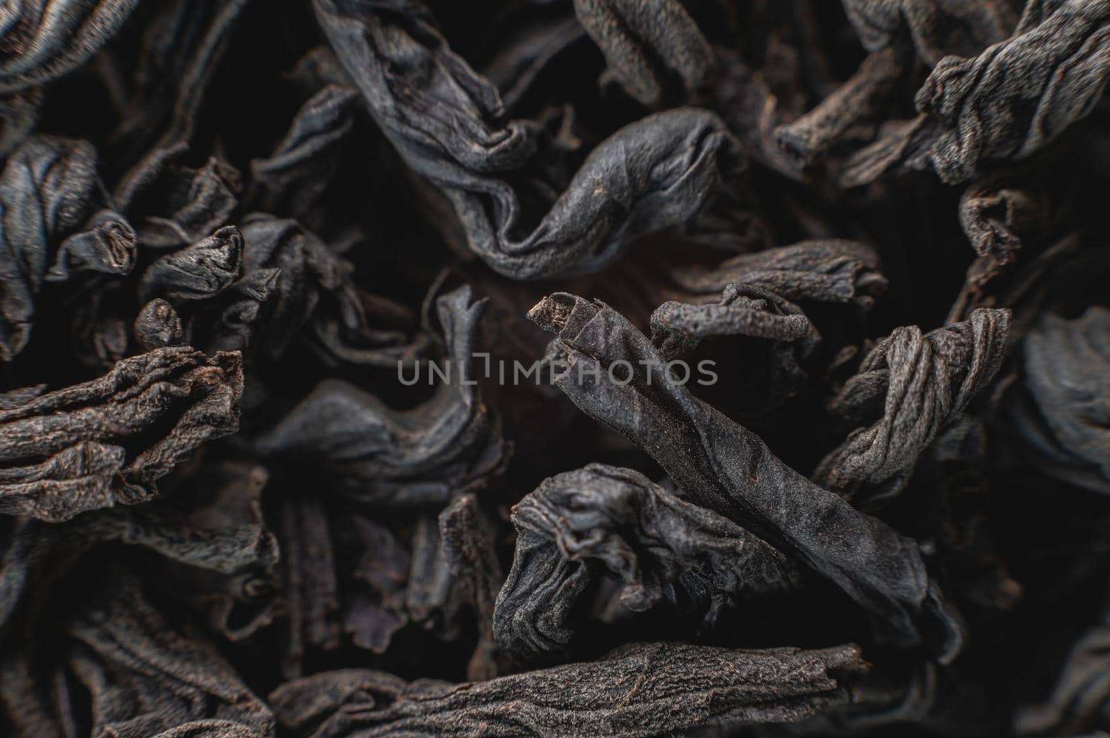 Extreme macro Black loose leaf tea as a background. Texture of dry black tea leaves in shallow depth of field. Dark background. macro mode. black leaf tea closeup.