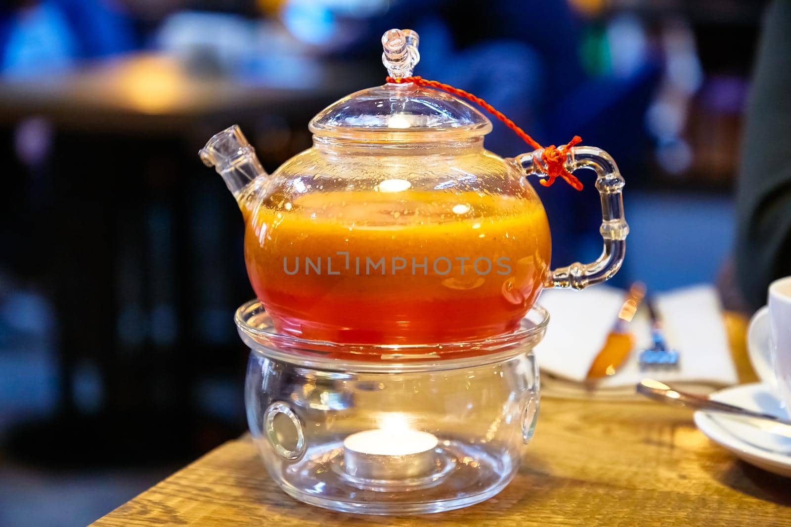 Red tea with sea buckthorn in a glass teapot.