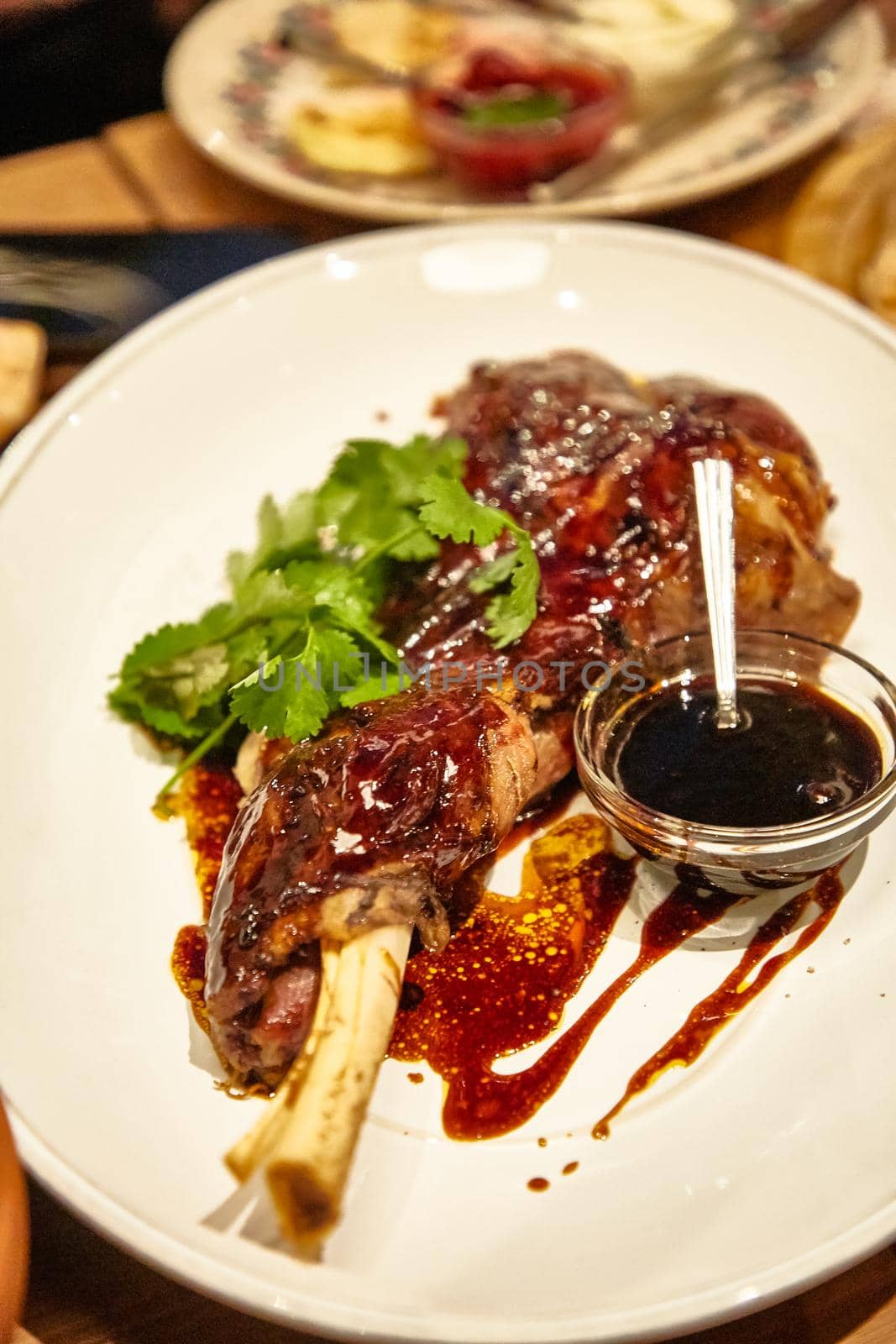 Stewed leg rabbit or duck is on a plate with sauce.