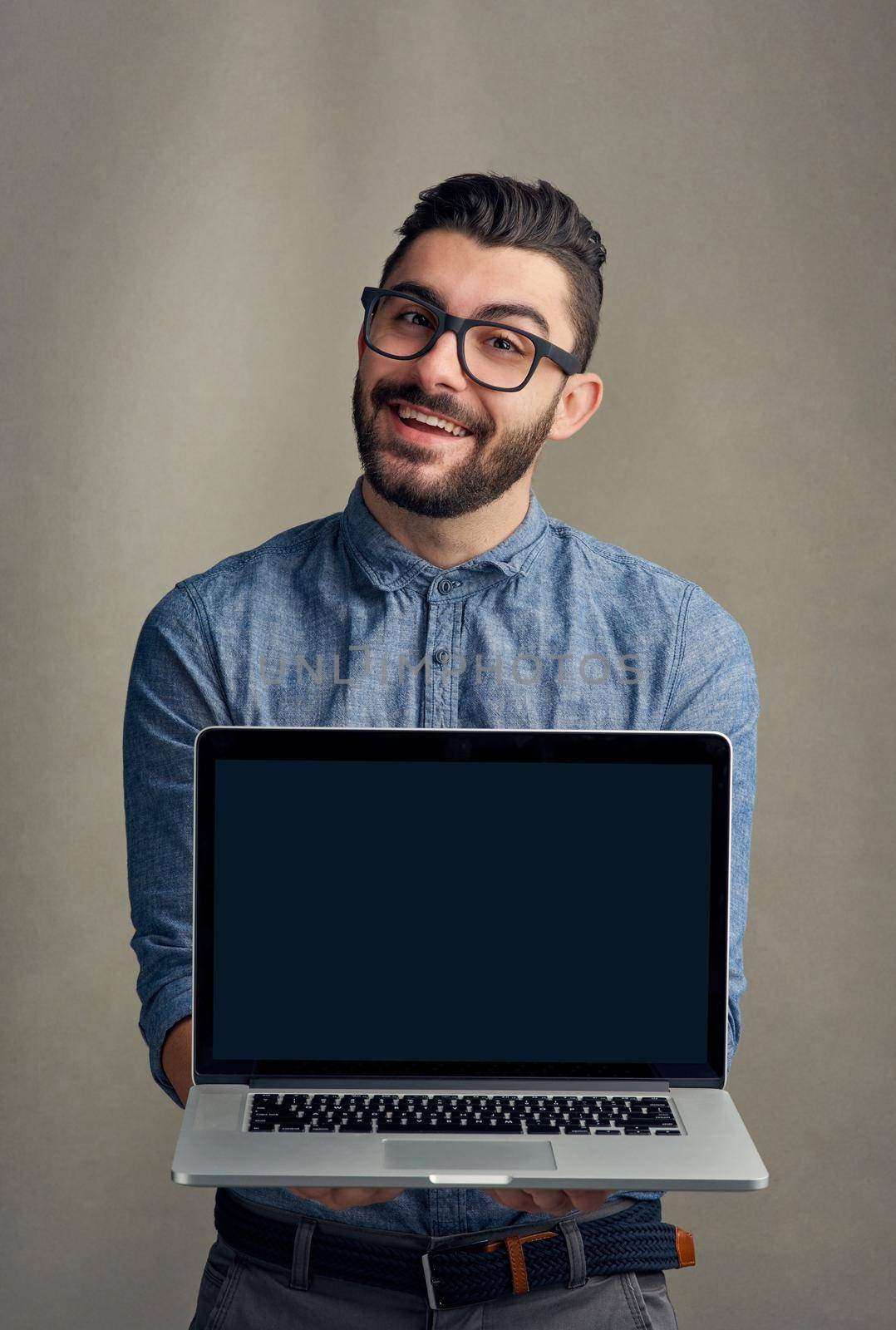 Your business website would look great here. Studio portrait of a young man holding a laptop against a grey background. by YuriArcurs