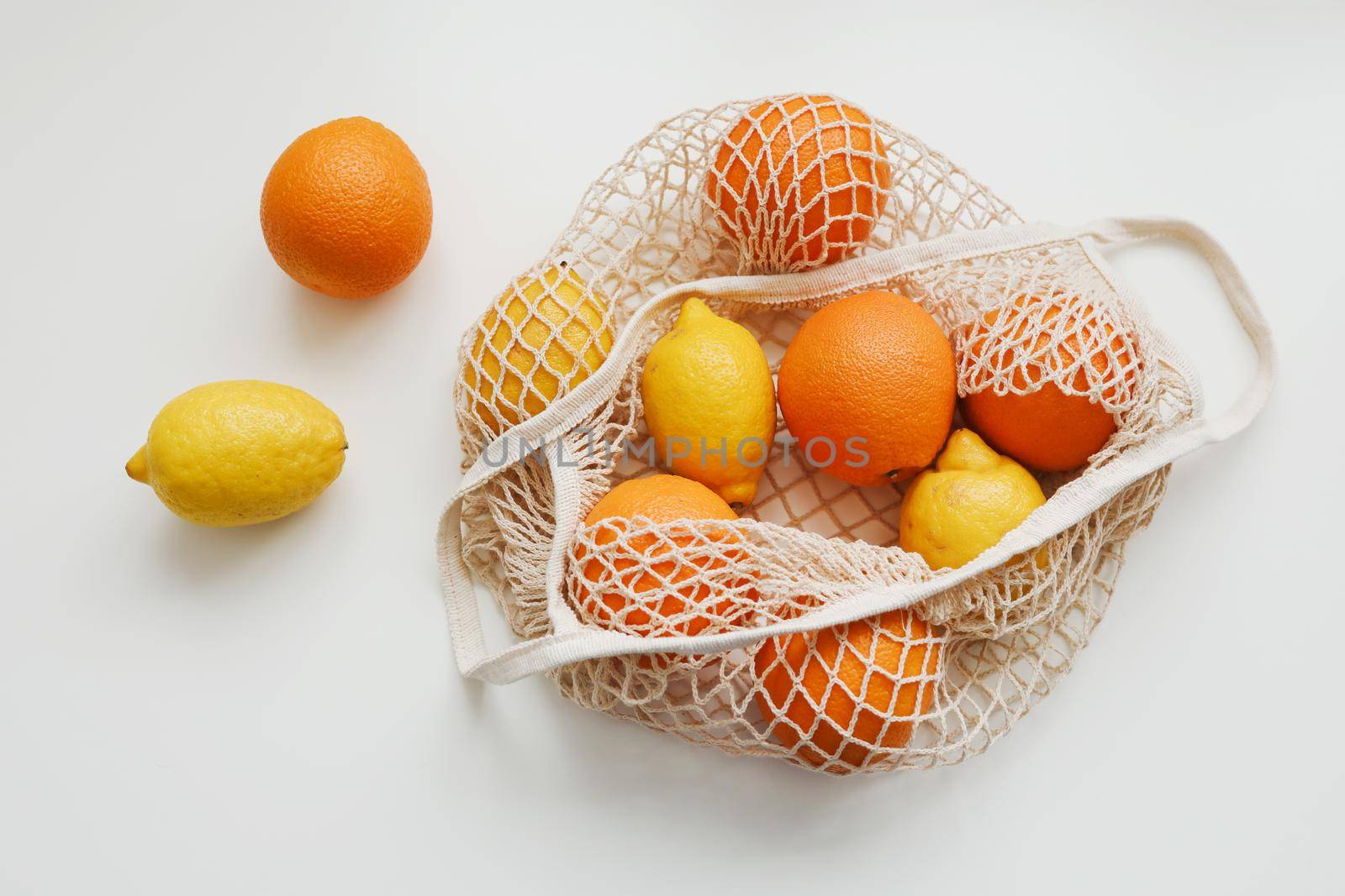 Lemons in reusable bag. Zero waste concept with string bag, mesh bag, grosery bag with fruits on white background, flat lay, top view, copy space.