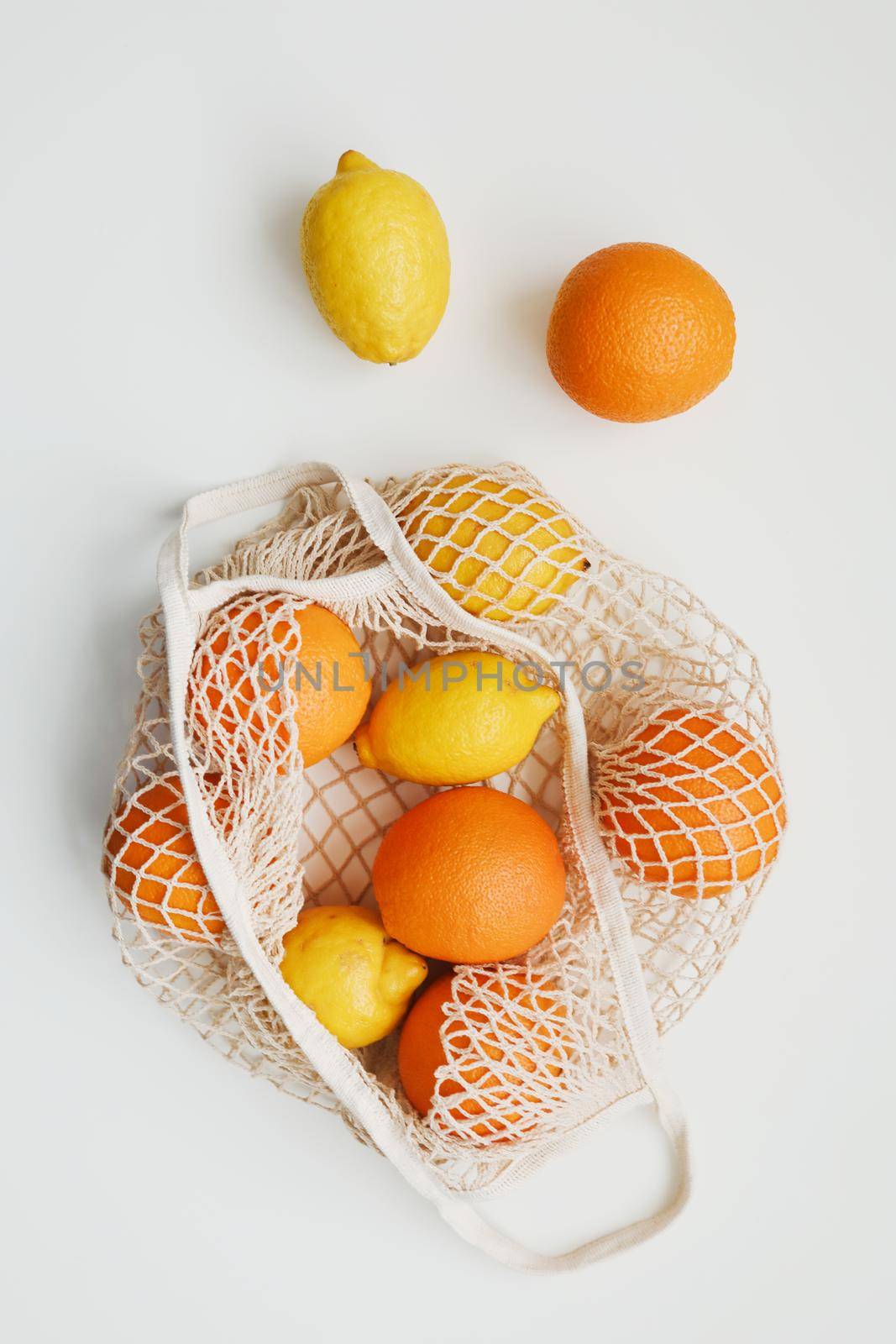 Lemons in reusable bag. Zero waste concept with string bag, mesh bag, grosery bag with fruits on white background, flat lay, top view, copy space.