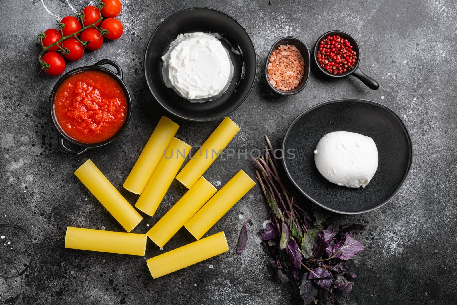 Cannelloni with spinach and ricotta set, on black dark stone table background, top view flat lay