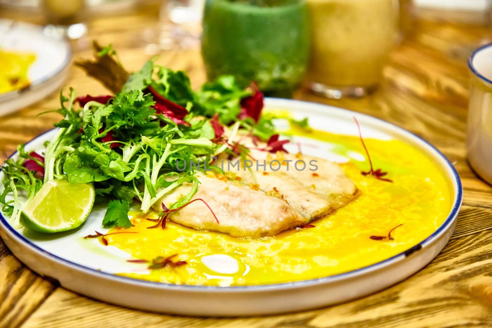 Fried fish with parsley, lettuce and sauce is on the plate by Milanchikov