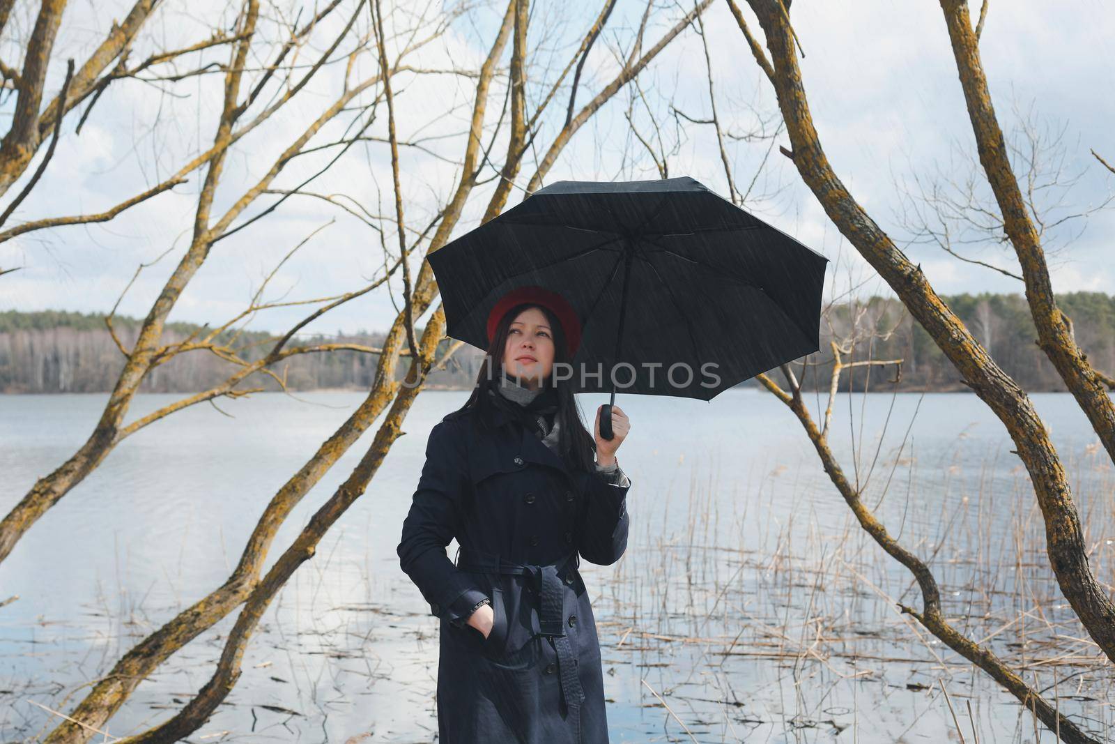 Portrait of a young nice woman with black umbrella on the beach outdoors