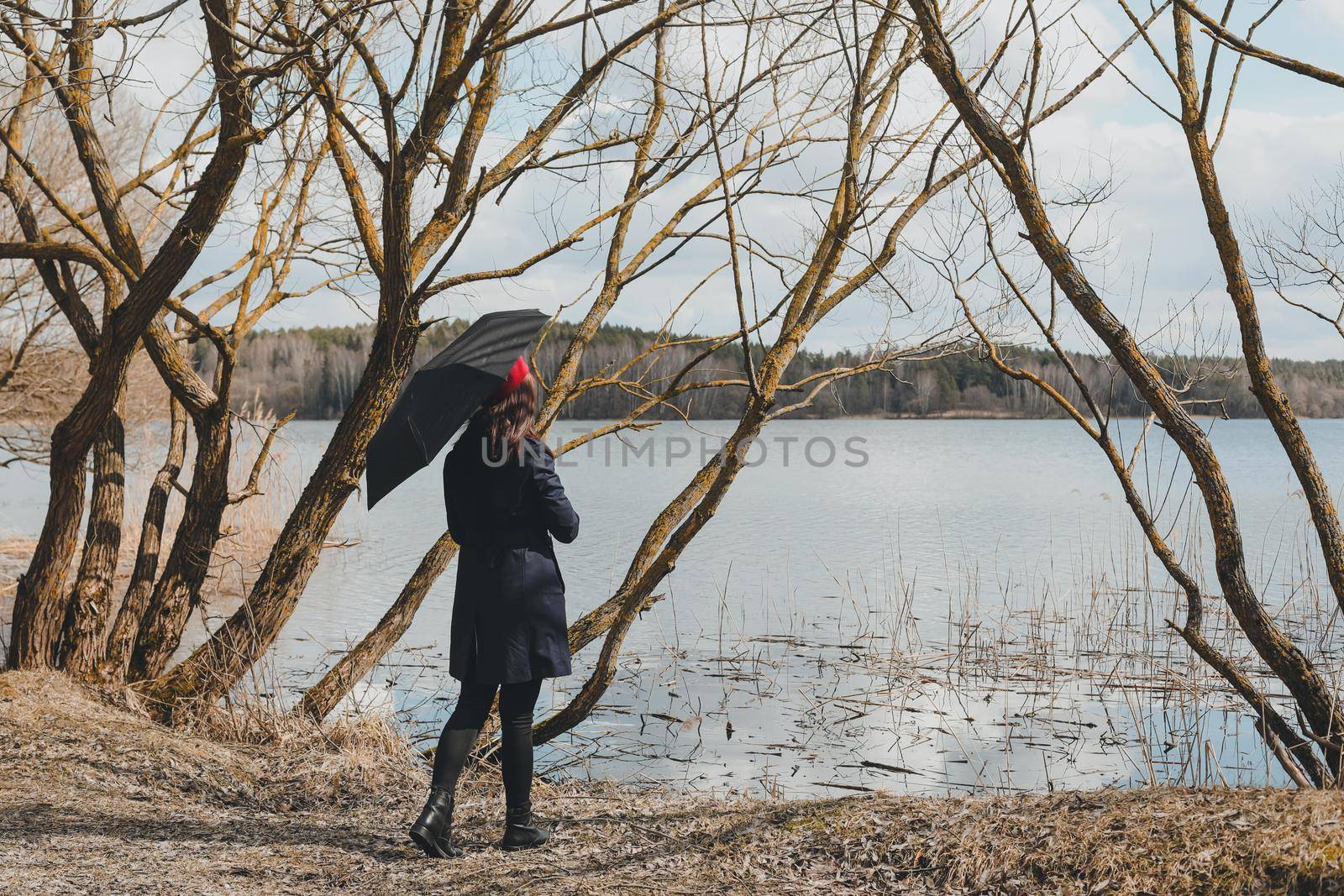 Portrait of a young nice woman with black umbrella on the beach outdoors