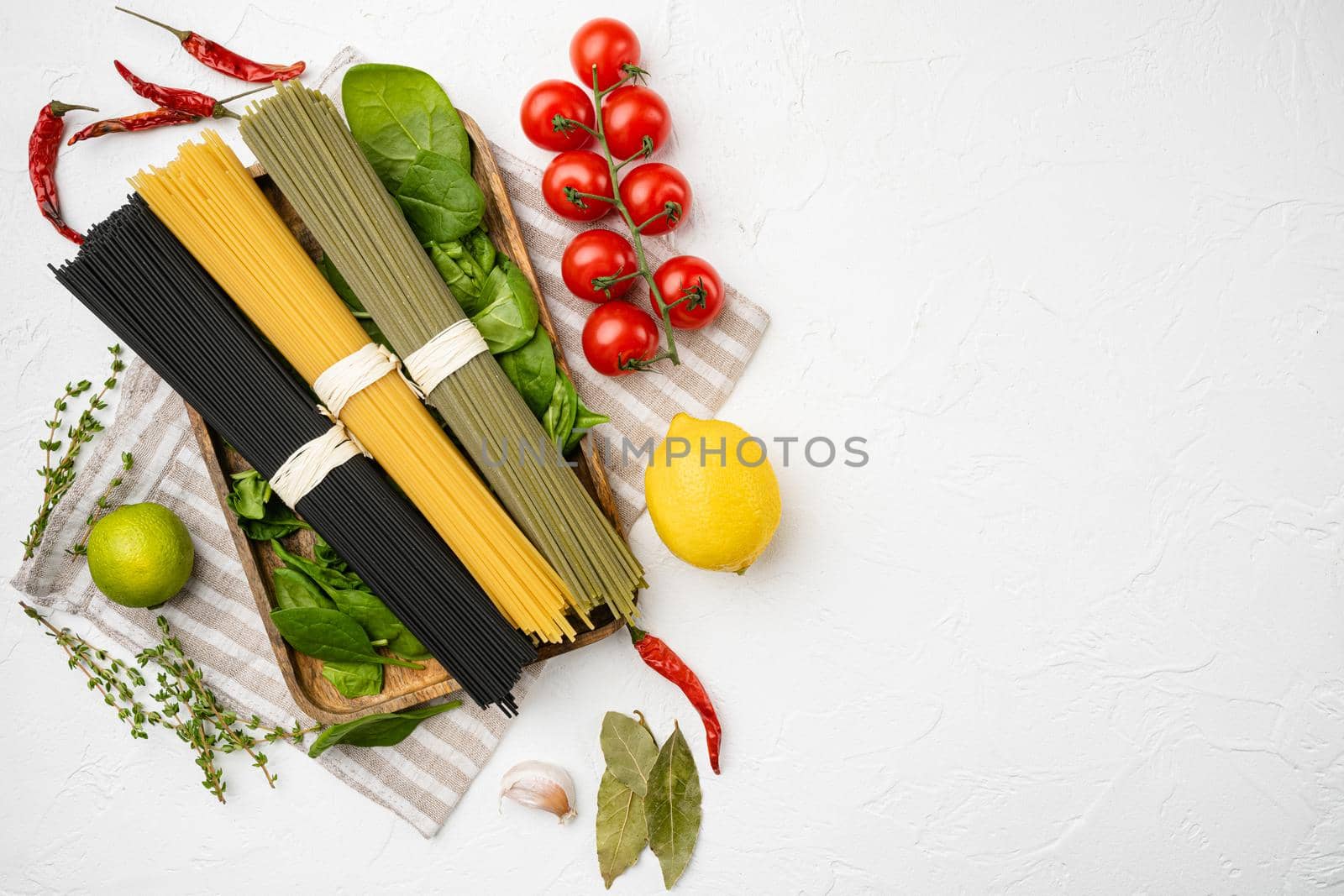 Colored spaghetti raw dry set, on white stone table background, top view flat lay, with copy space for text