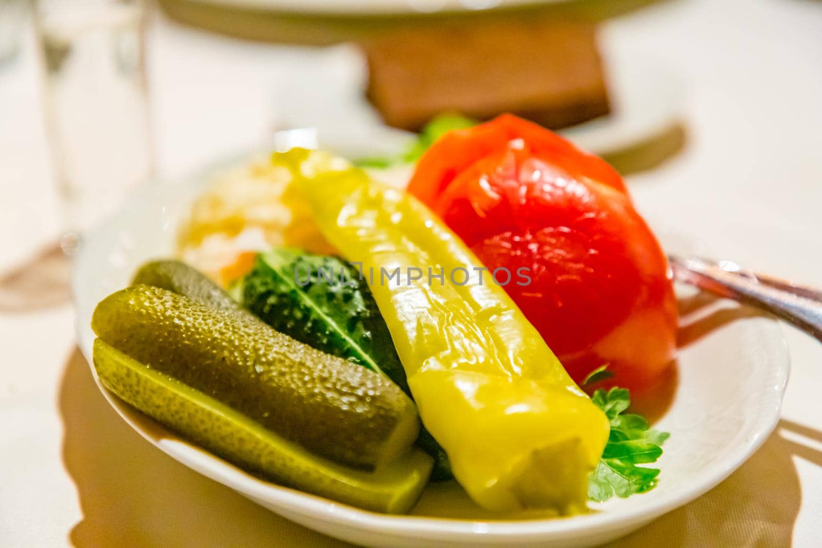 Traditional Russian snacks (pickles, tomatoes, sauerkraut) are on the plate.