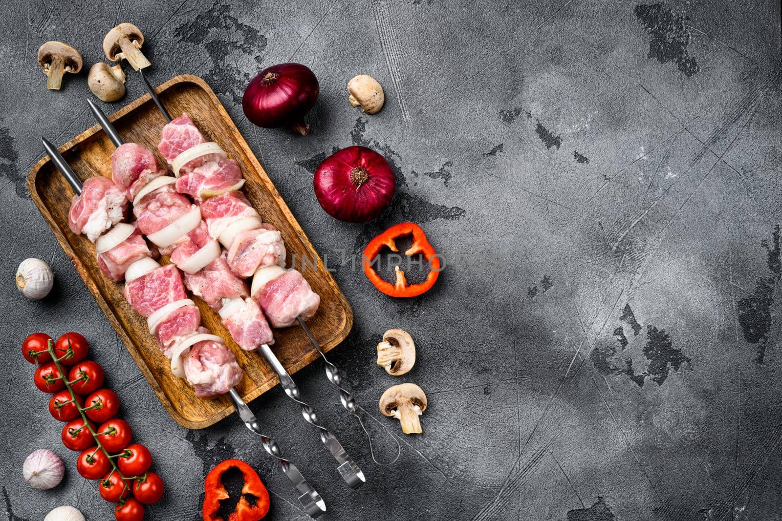 Raw pork shish kebab. BBQ meat with vegetables set, top view flat lay, with copy space for text, on gray stone table background