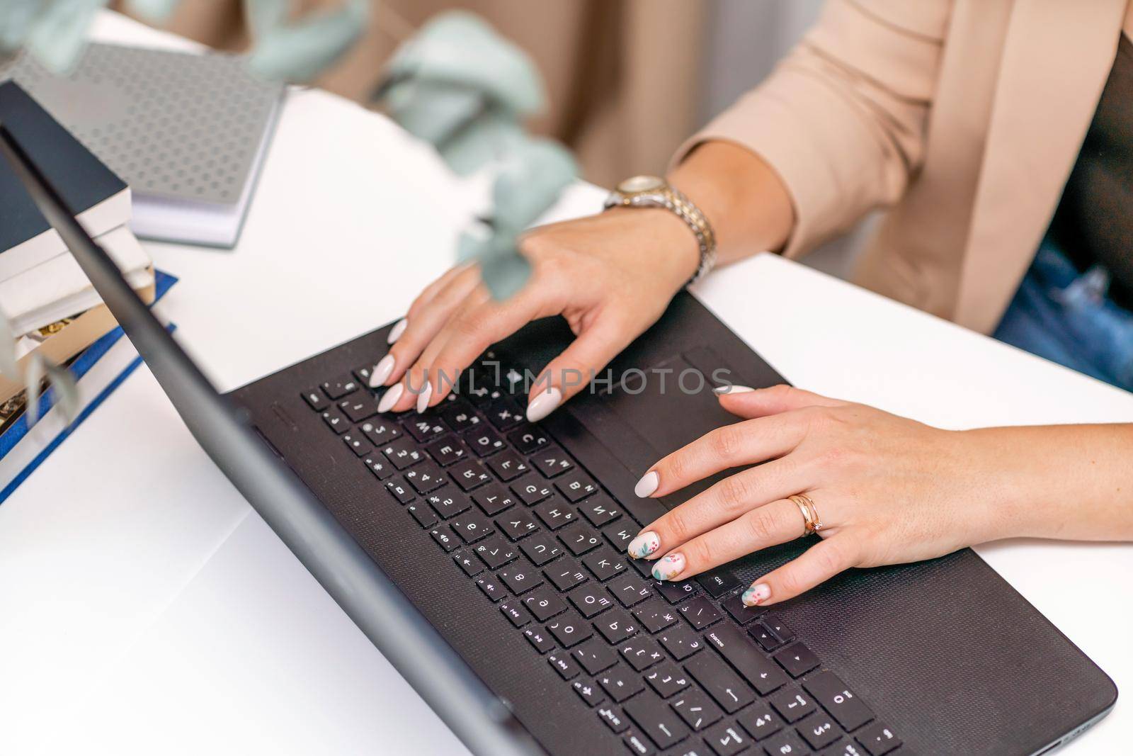 European professional woman sitting with laptop at home office desk, positive woman studying while working on PC. She is wearing a red plaid shirt and jeans